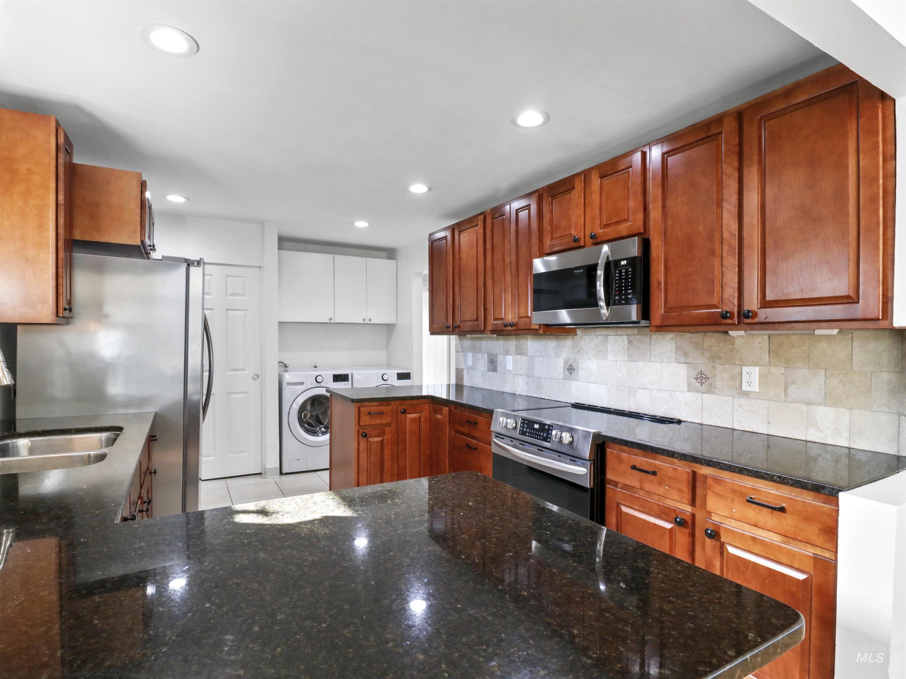 Kitchen with brown cabinets, dark stone counters, and recessed lighting