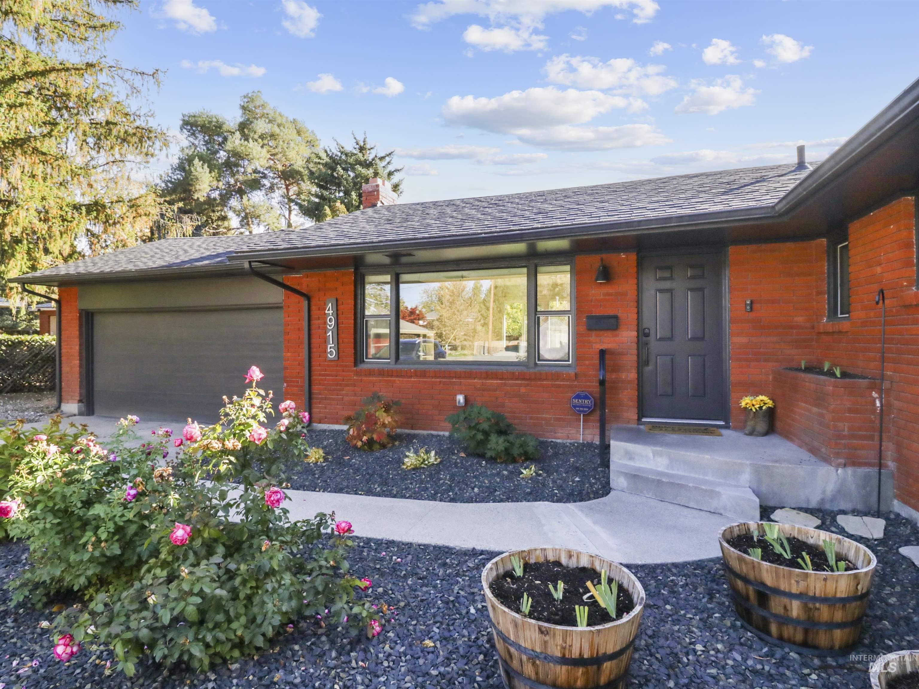 View of front of home featuring an attached garage, a chimney, and brick siding