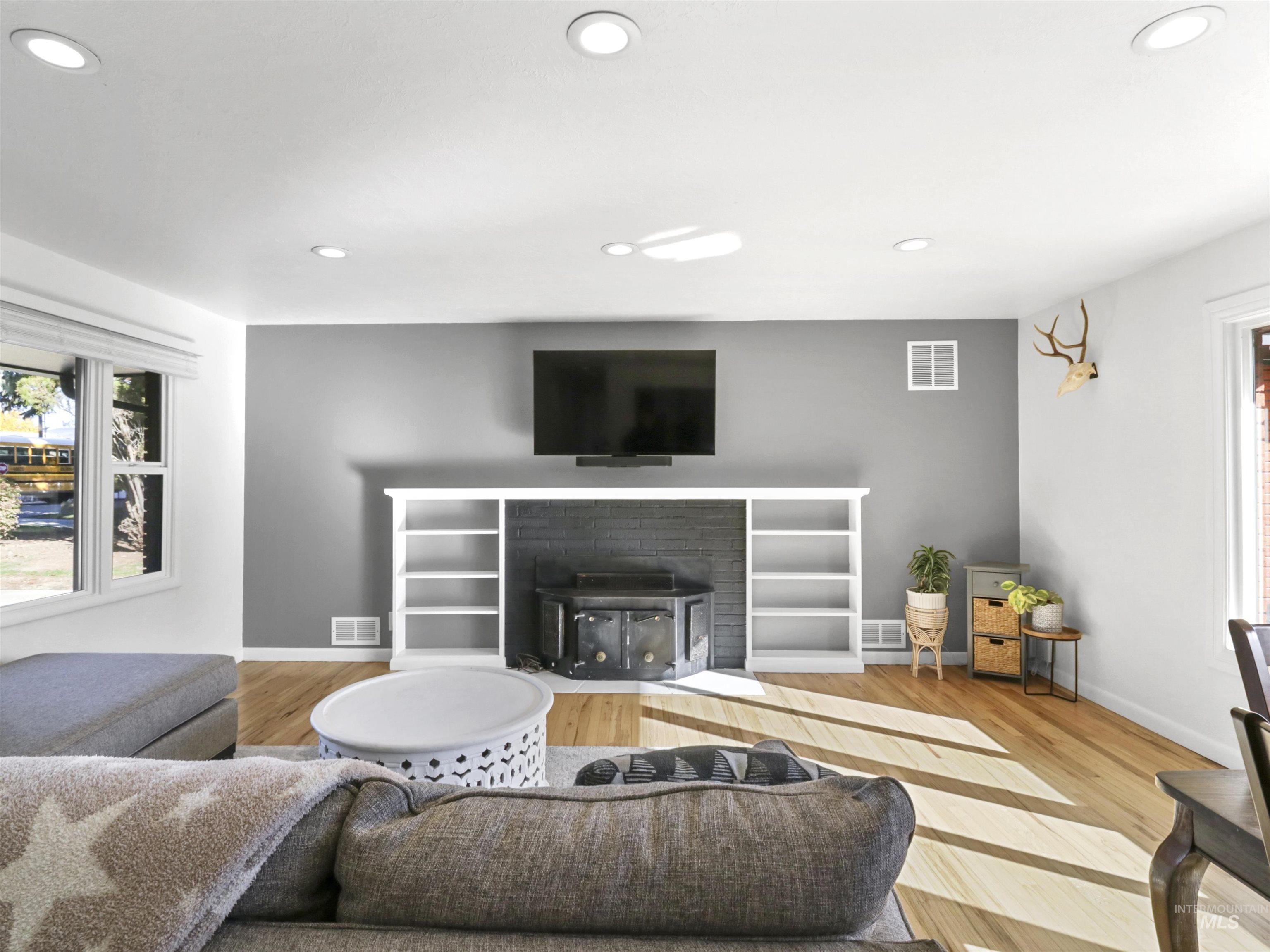 Living room with plenty of natural light, recessed lighting, light wood finished floors, and a fireplace with flush hearth