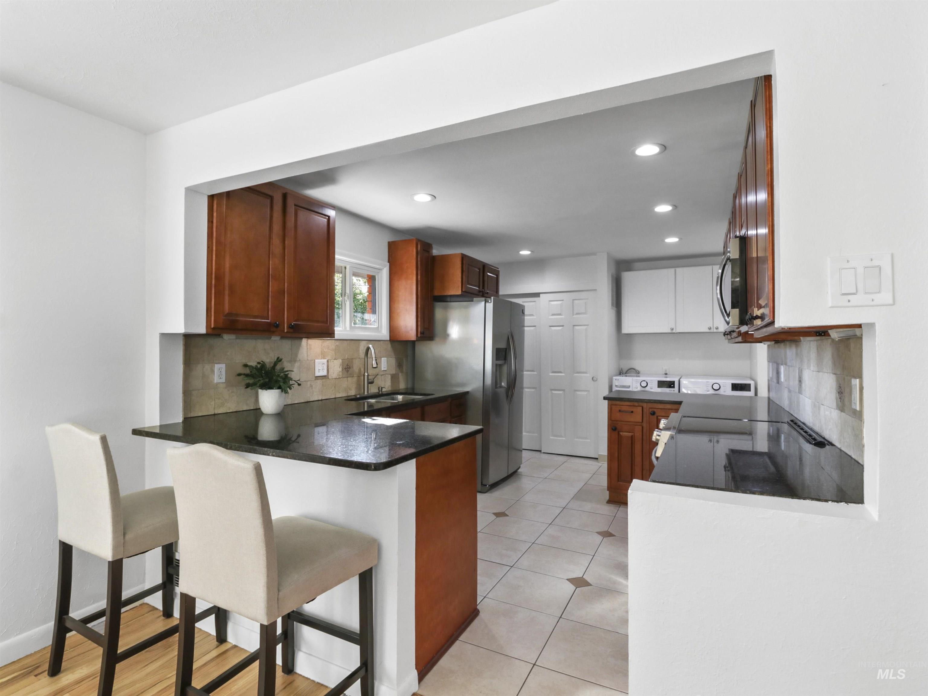 Kitchen featuring decorative backsplash, brown cabinets, a kitchen breakfast bar, a peninsula, and recessed lighting