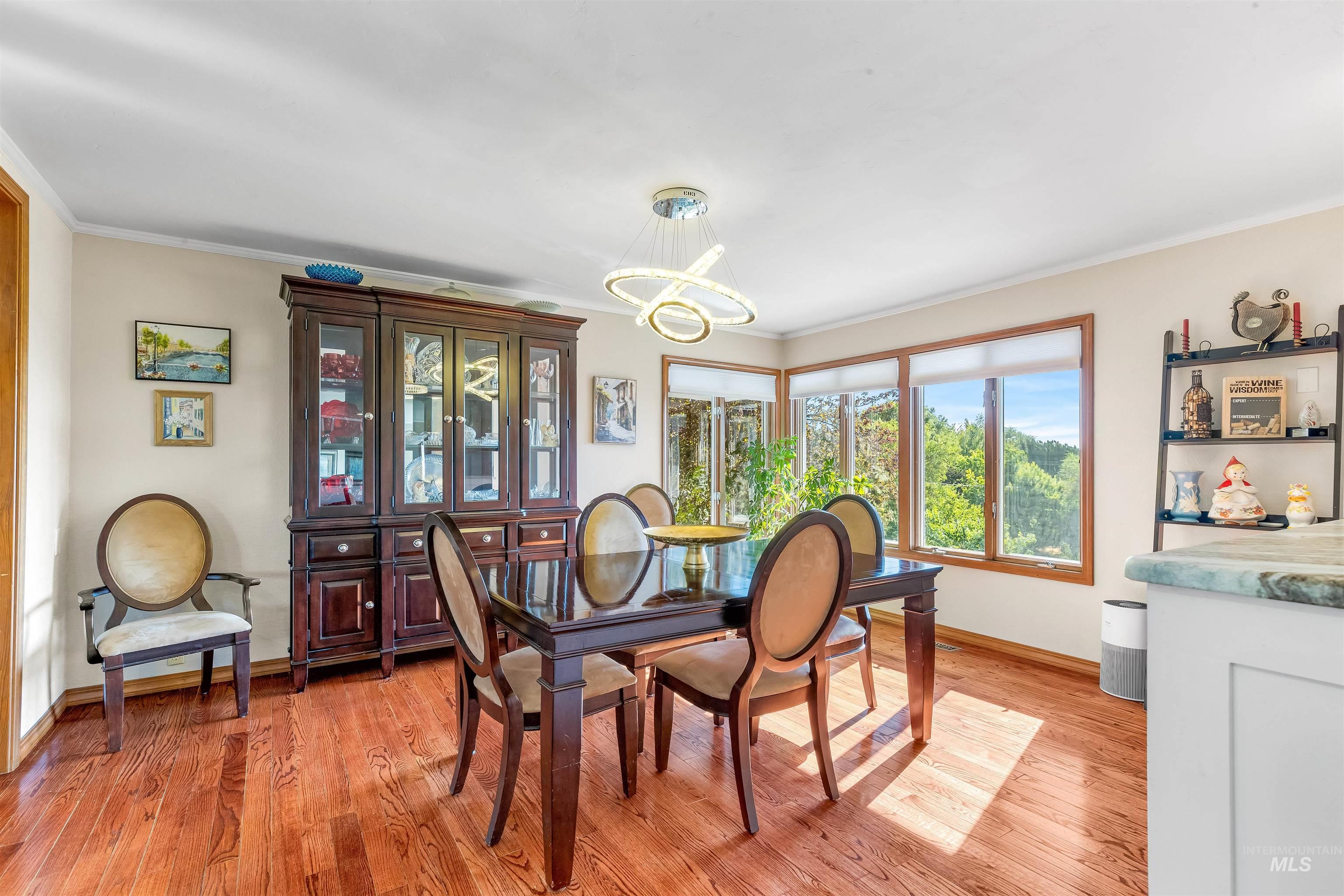Dining area featuring light wood finished floors, ornamental molding, and a chandelier