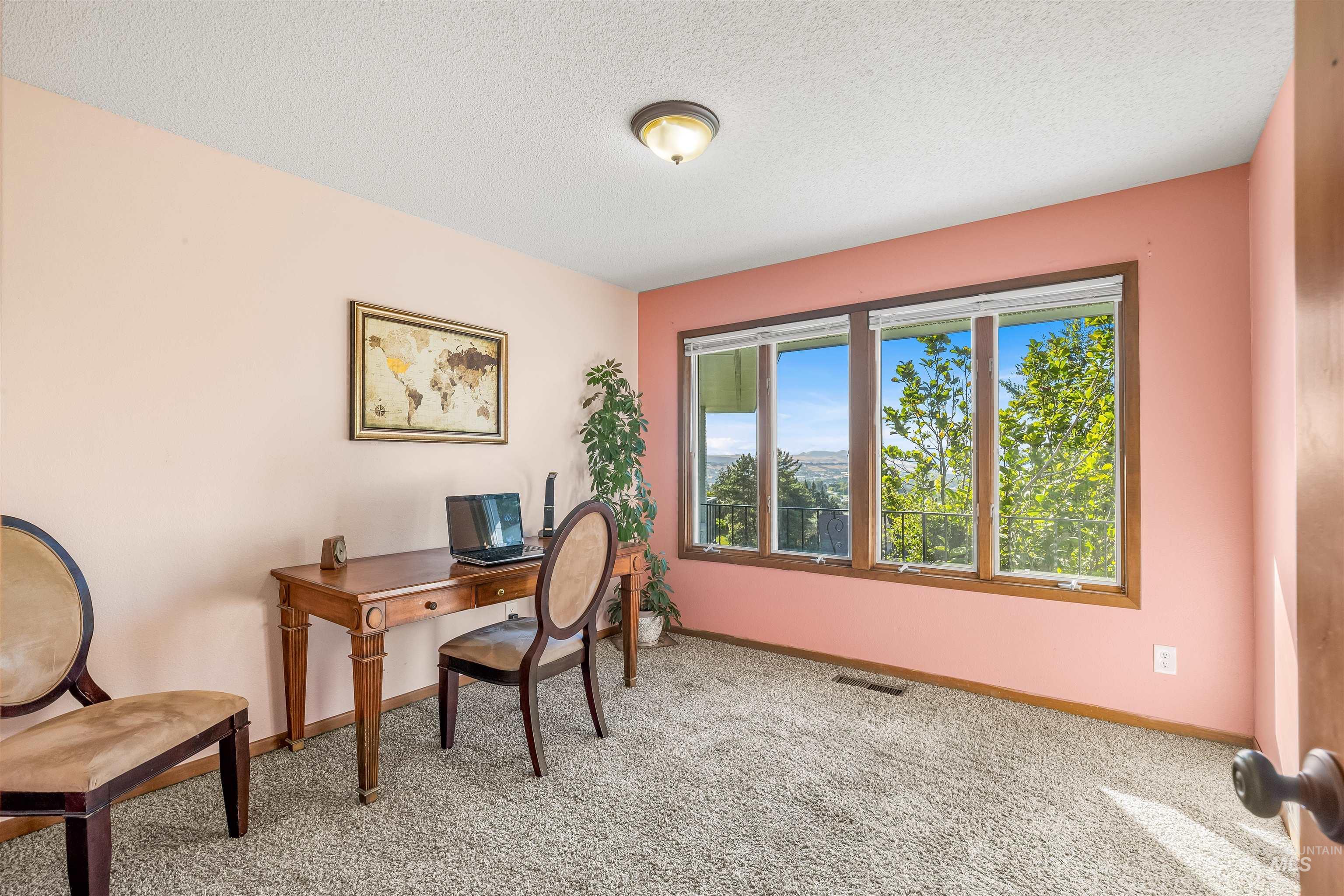 Carpeted office featuring a textured ceiling and baseboards