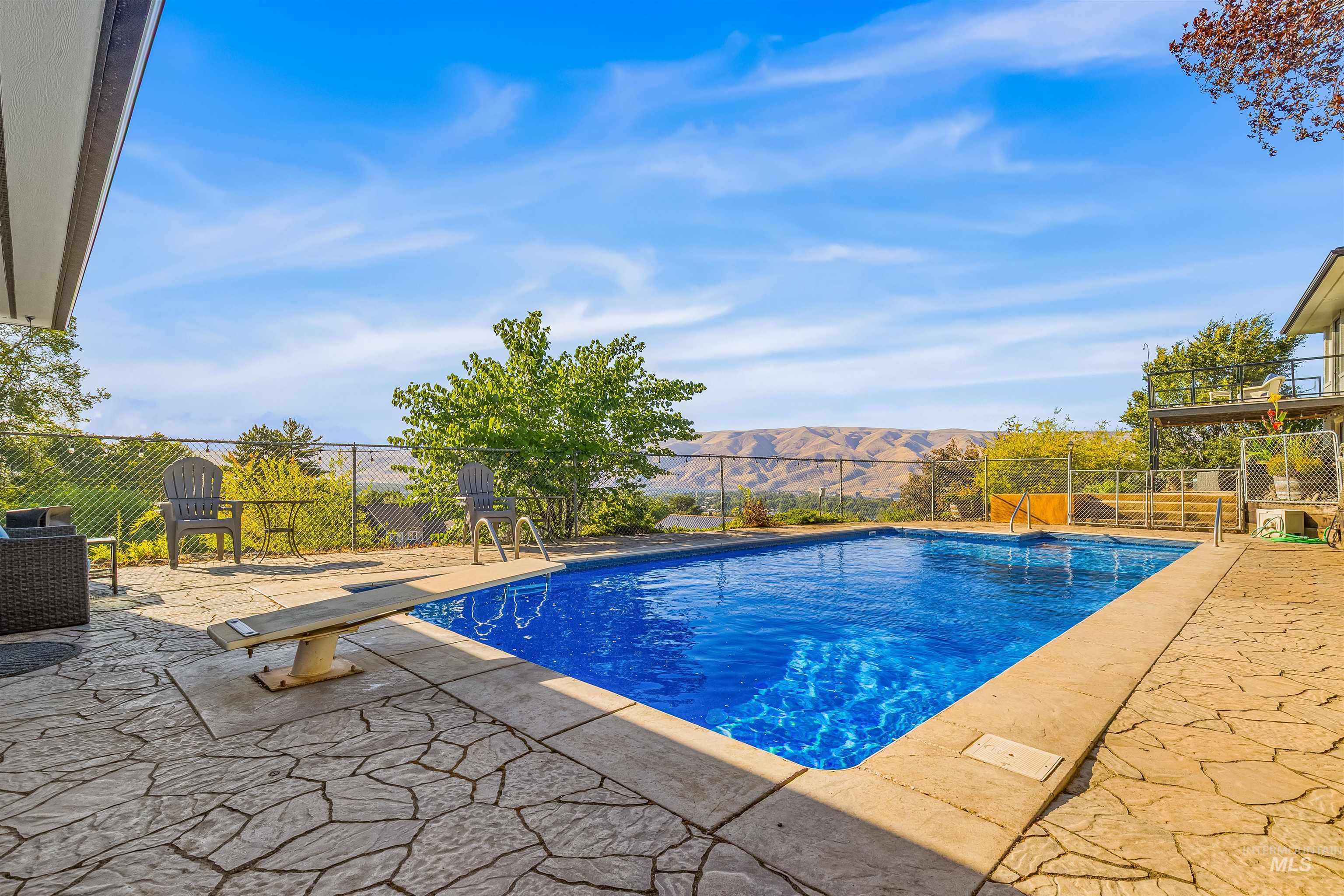View of pool with a patio area, a mountain view, and a diving board
