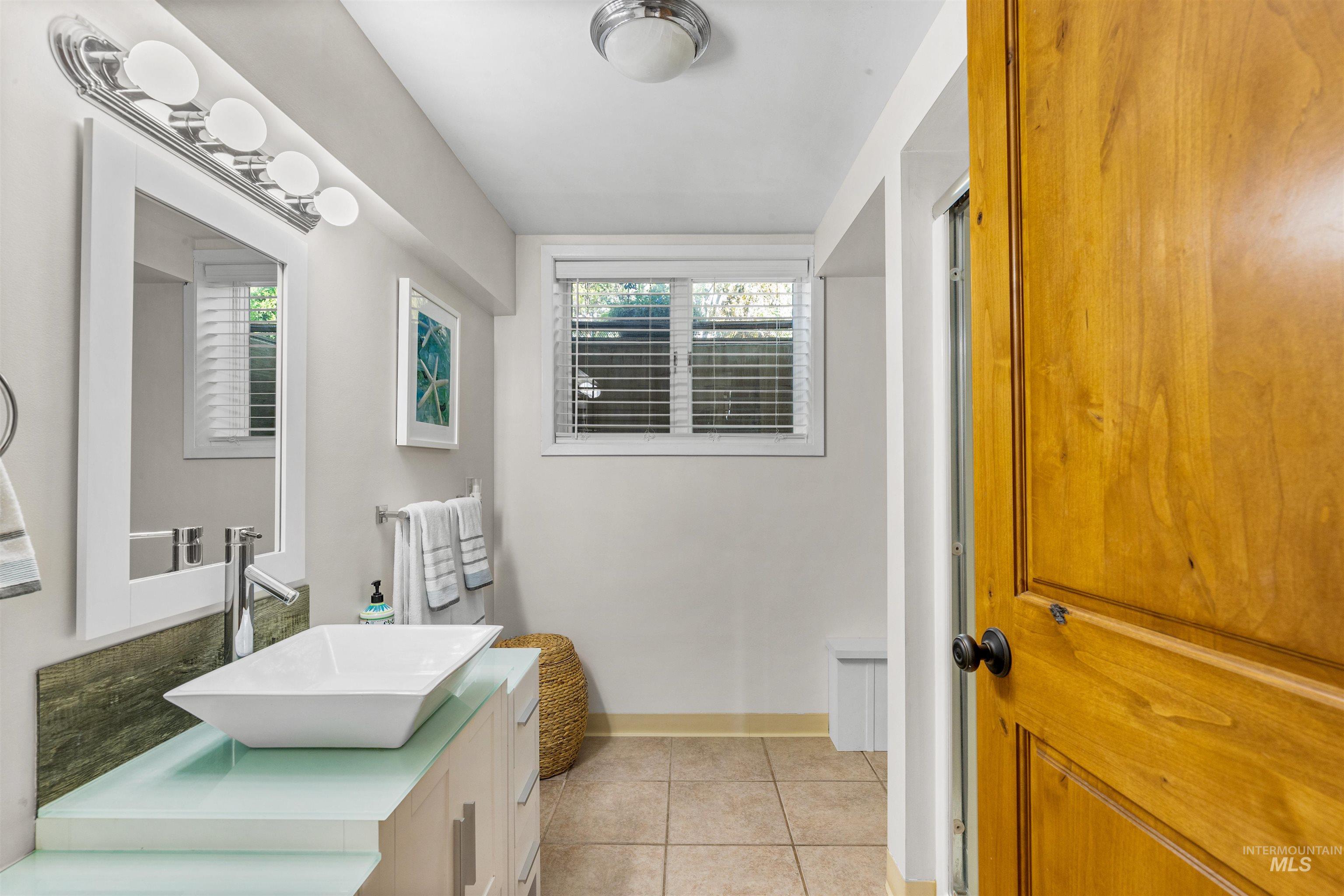 Bathroom with light tile patterned floors and vanity