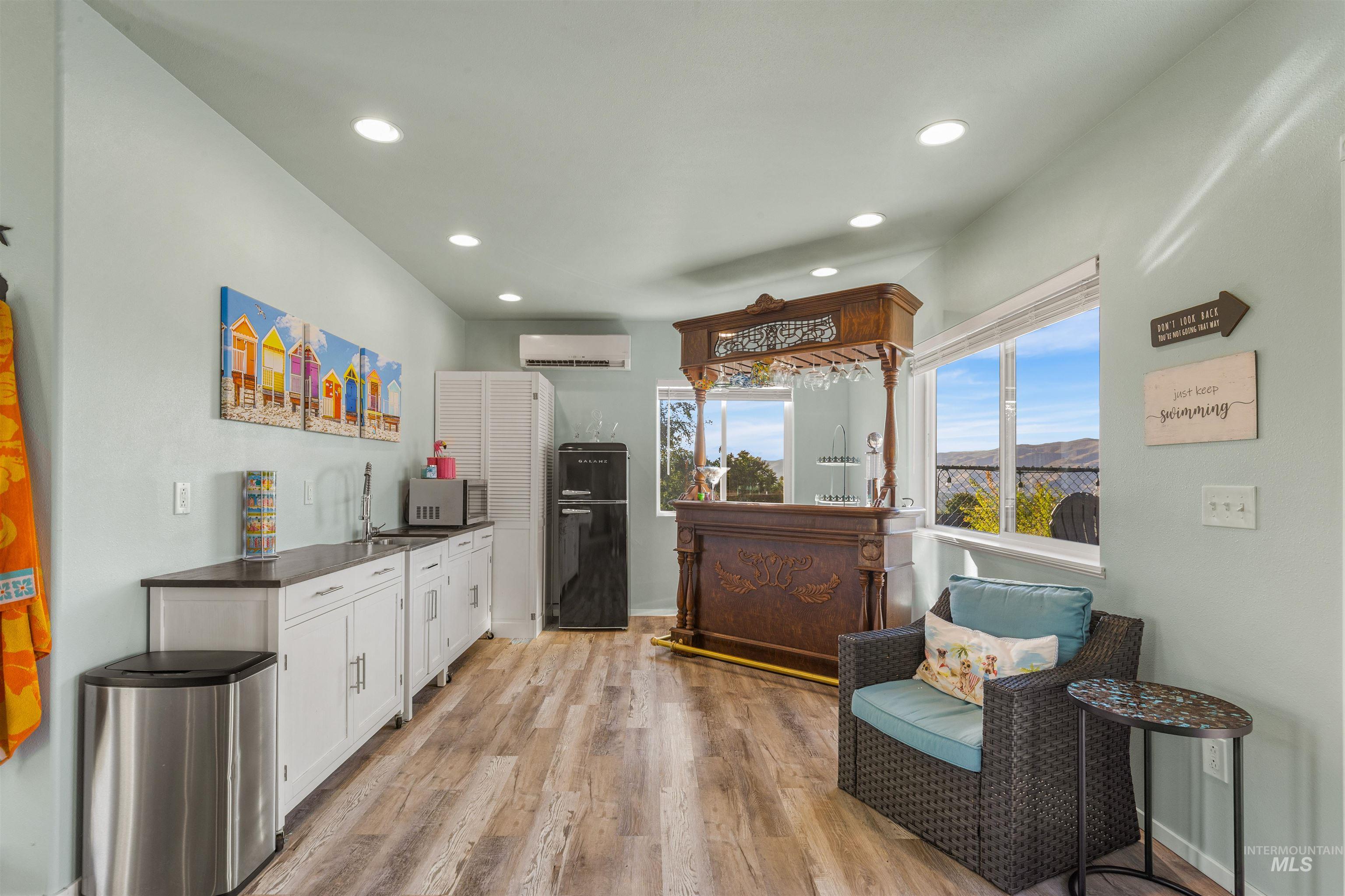 Kitchen with white cabinetry, dark countertops, light wood-style flooring, recessed lighting, and a wall unit AC