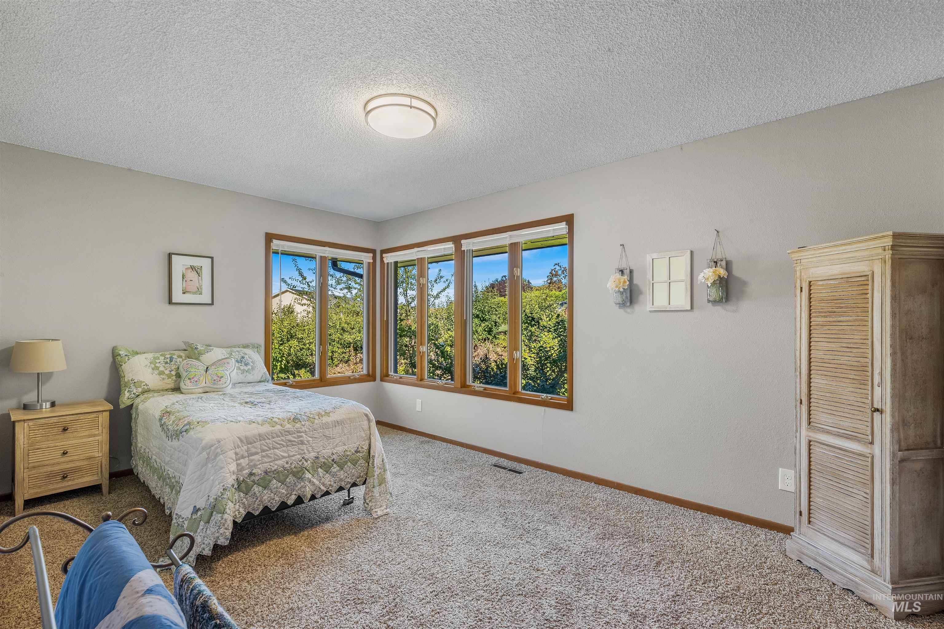 Carpeted bedroom with a textured ceiling and baseboards