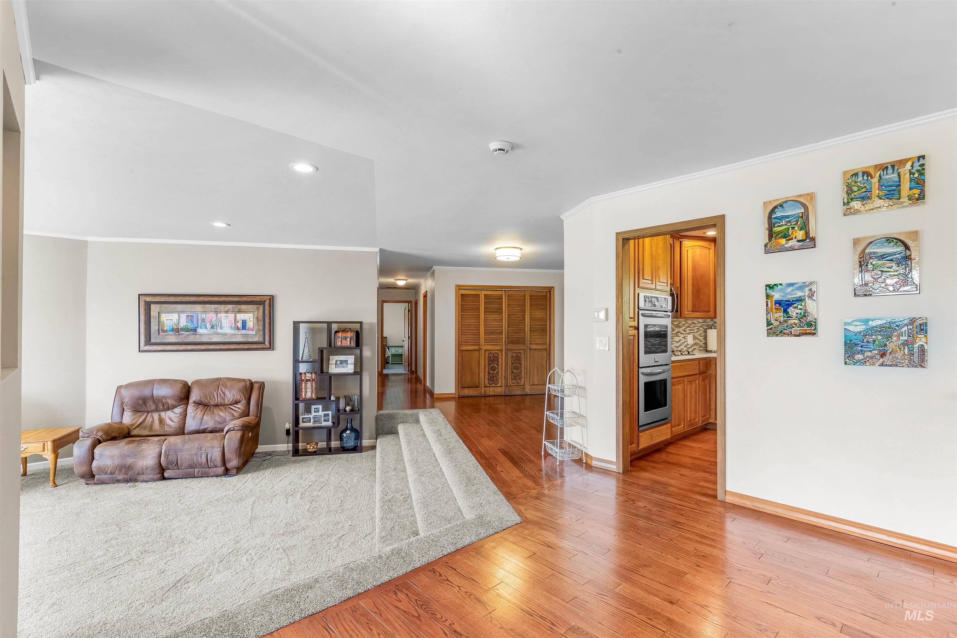 Living room with crown molding, light wood-style floors, and recessed lighting