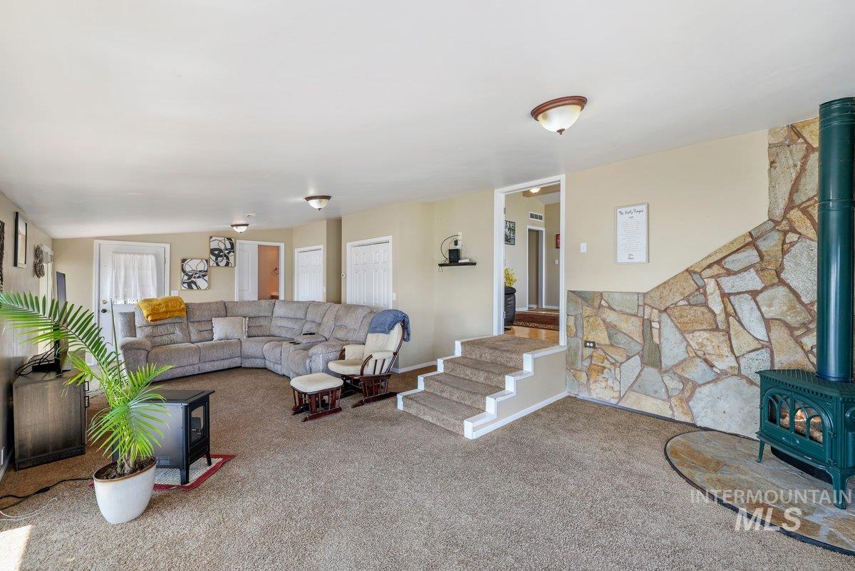 Carpeted living area featuring a wood stove and stairs