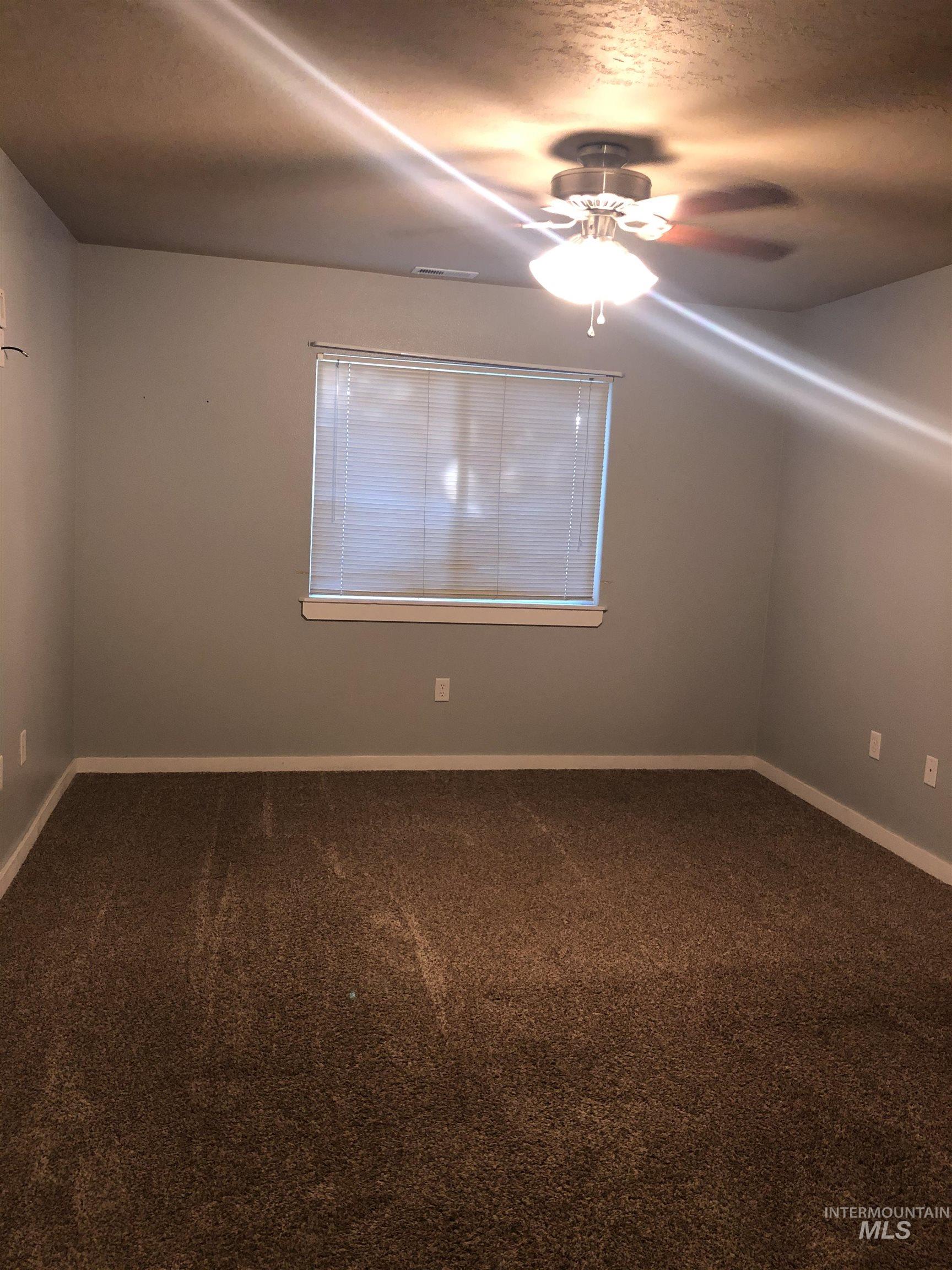 Neutral wall paint, brown carpet flooring, and a ceiling fan with integrated lighting