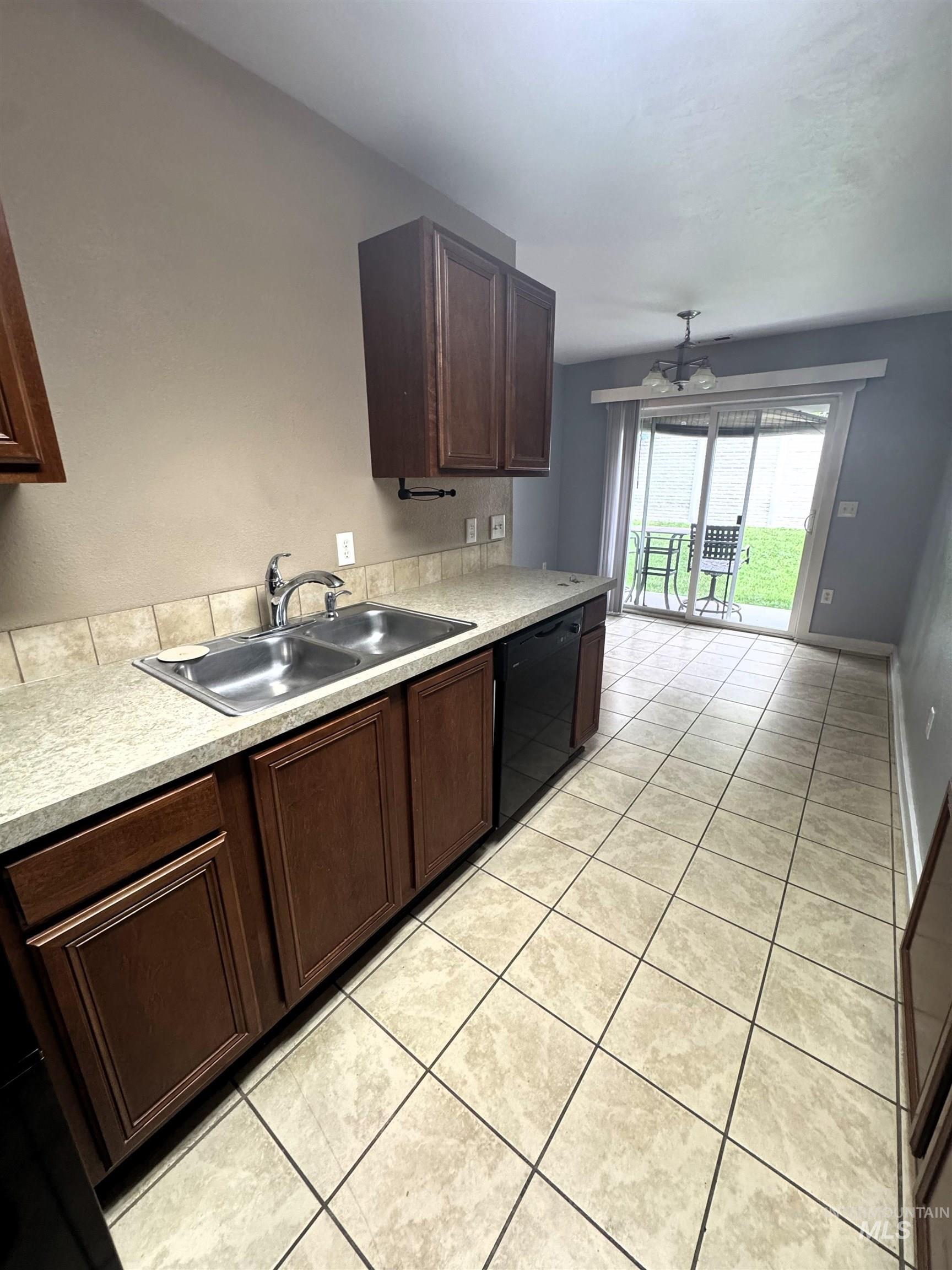 Kitchen featuring wood cabinetry, a double basin stainless steel sink, and a black built-in dishwasher