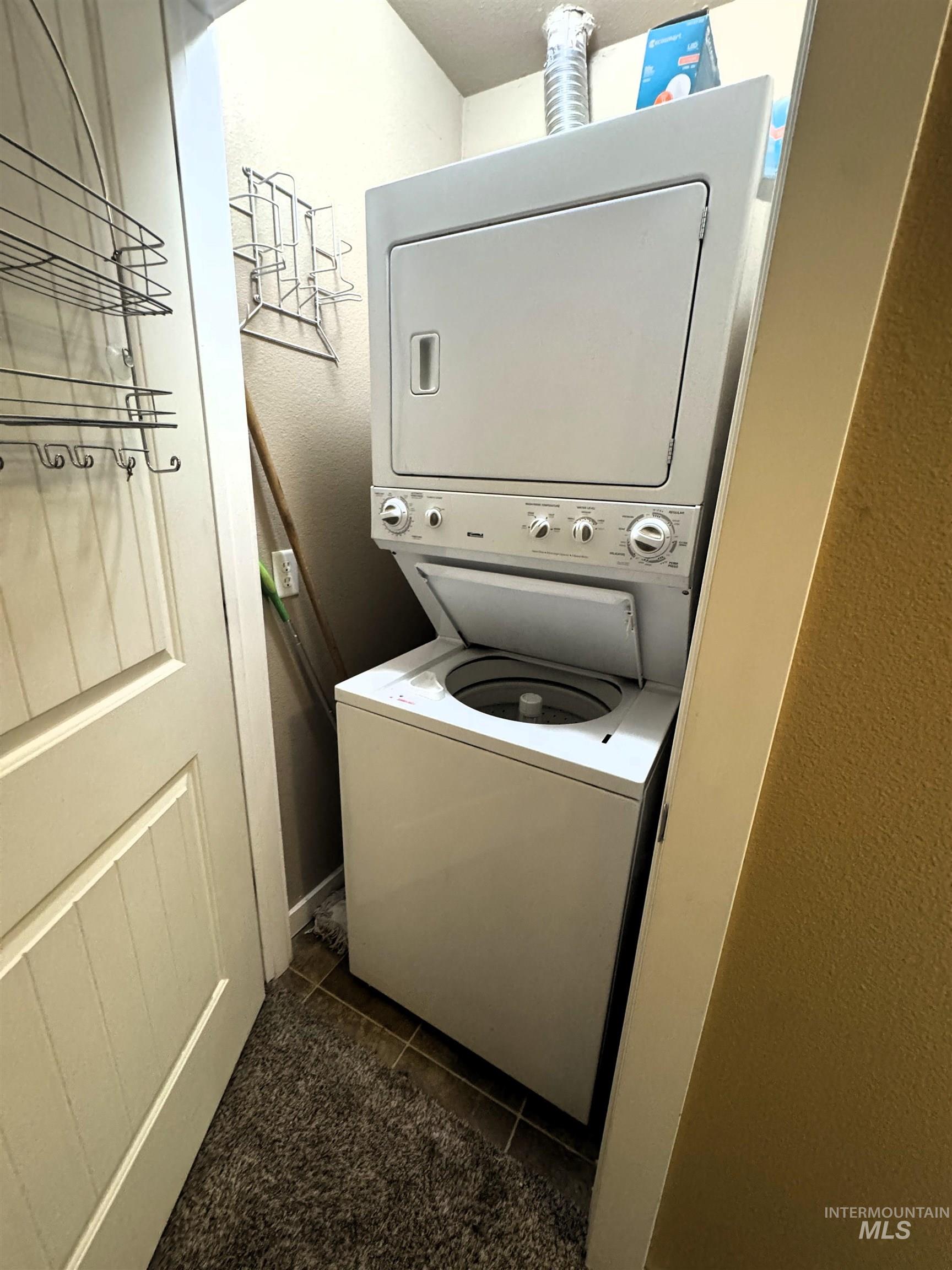 Dedicated laundry area featuring a stacked washer and dryer unit, tiled flooring, and a white paneled door