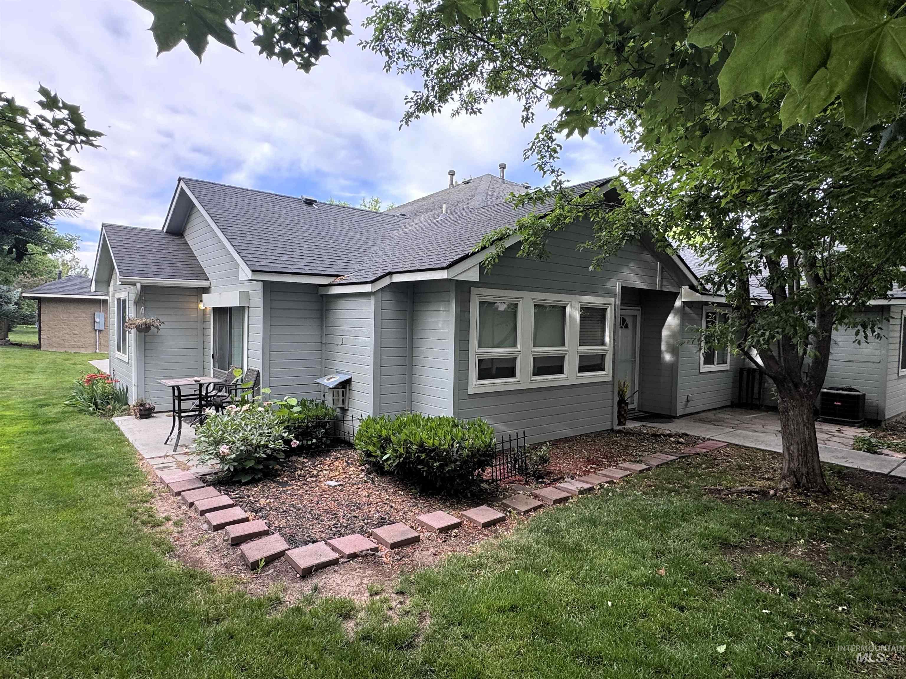 Exterior featuring light gray siding with white trim, a dark shingle roof, and multiple windows