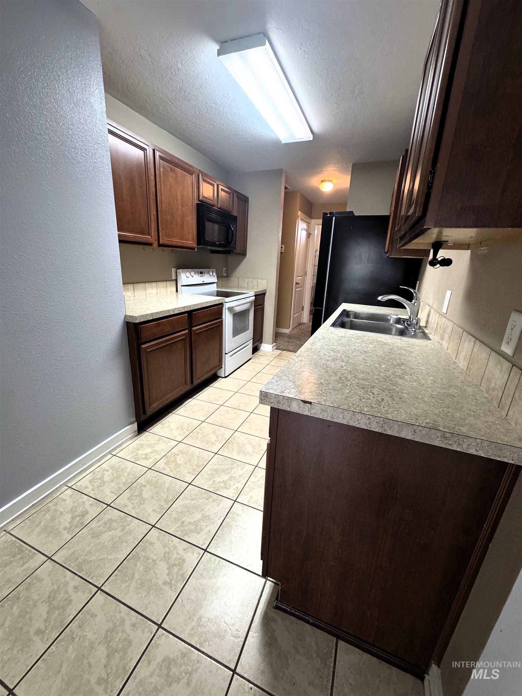 Kitchen featuring wood-finish cabinetry, tile flooring, and a stone-look countertop