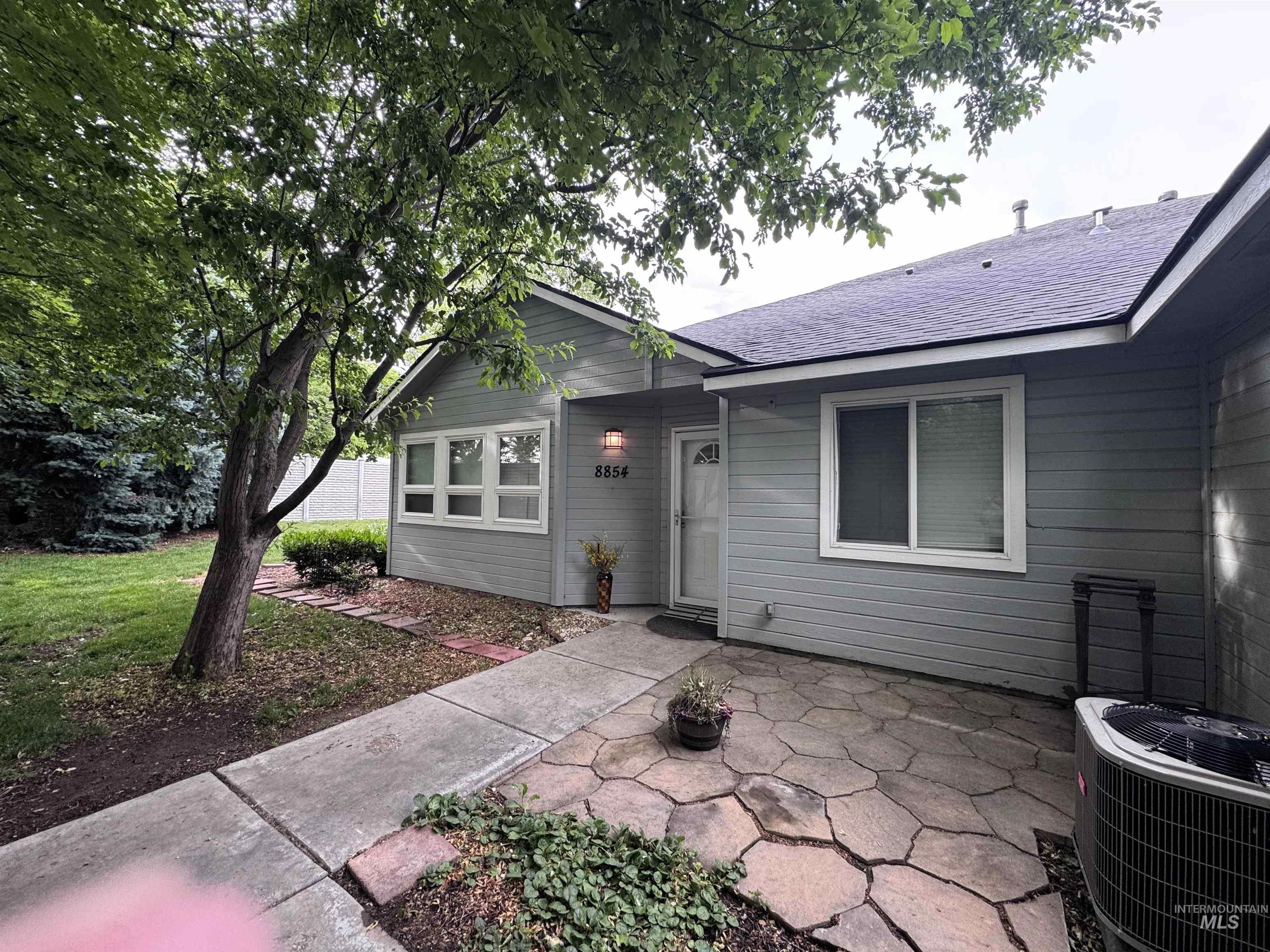 Light gray exterior with white trim windows and a stone paver patio