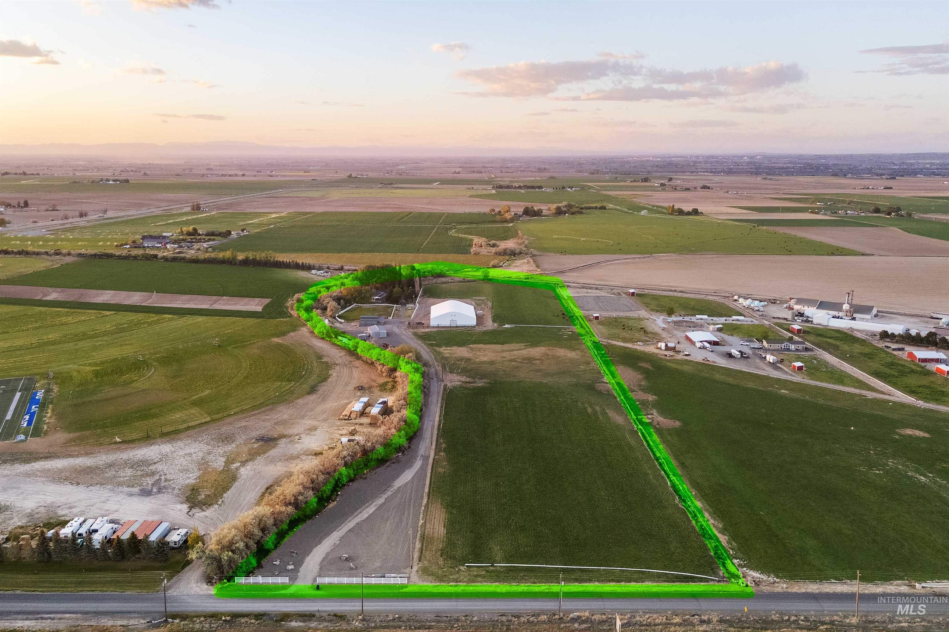 Expansive agricultural land featuring a large, level field and established perimeter trees