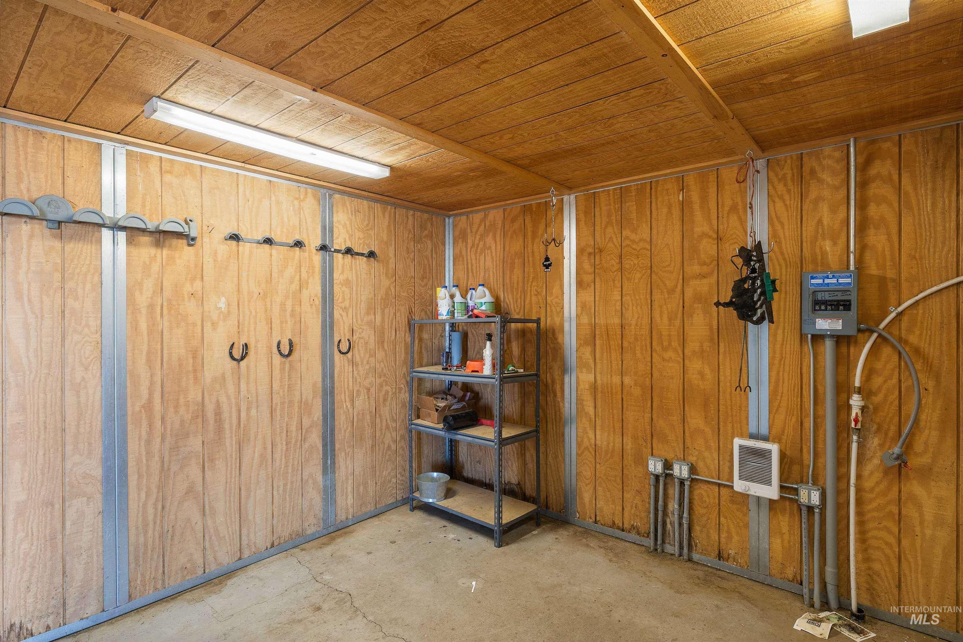 Utility room featuring wood-finish paneling, concrete flooring, and ceiling-mounted fluorescent lighting