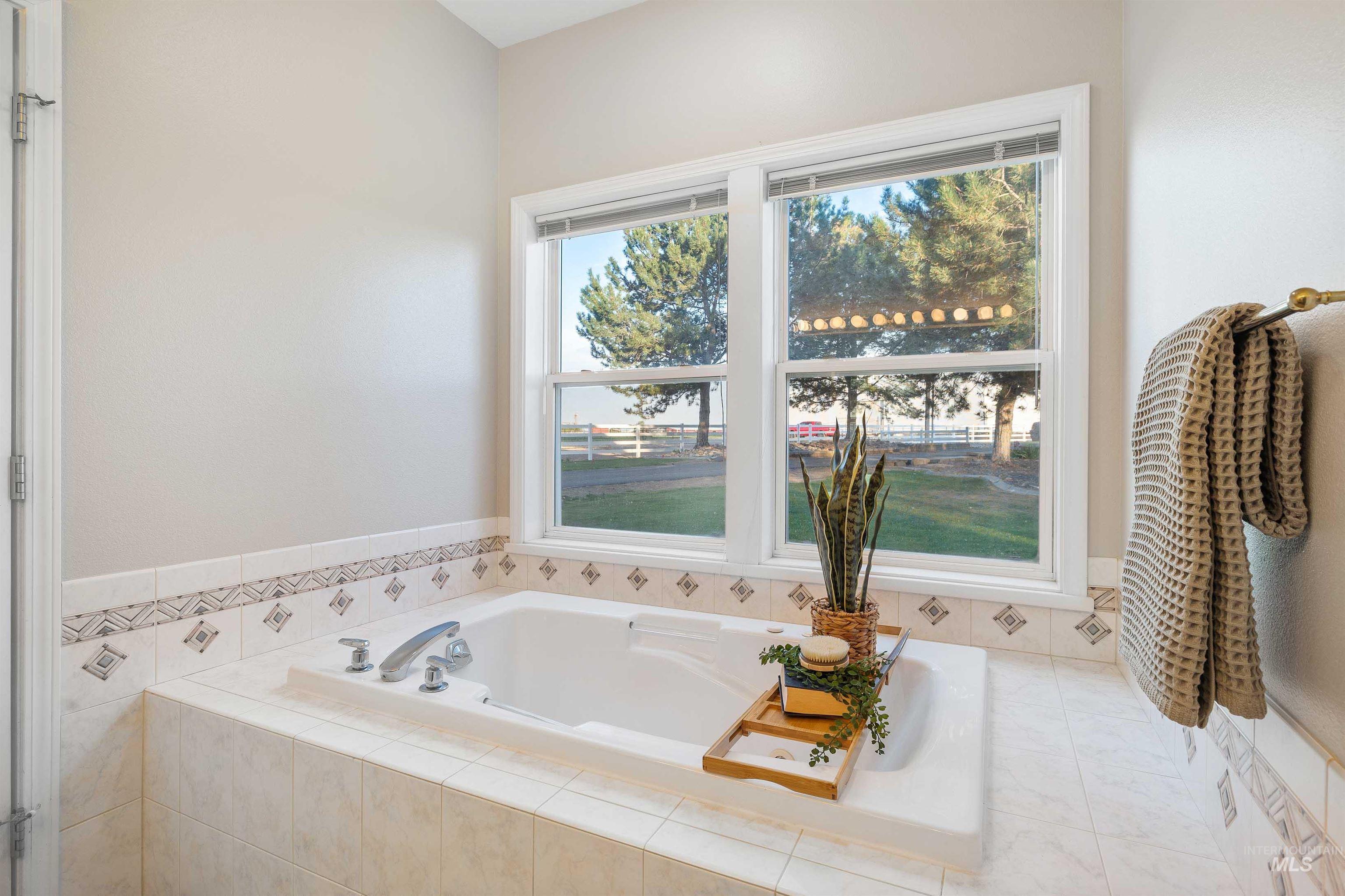 Recessed soaking tub with surrounding tiled deck, framed by a two-pane window