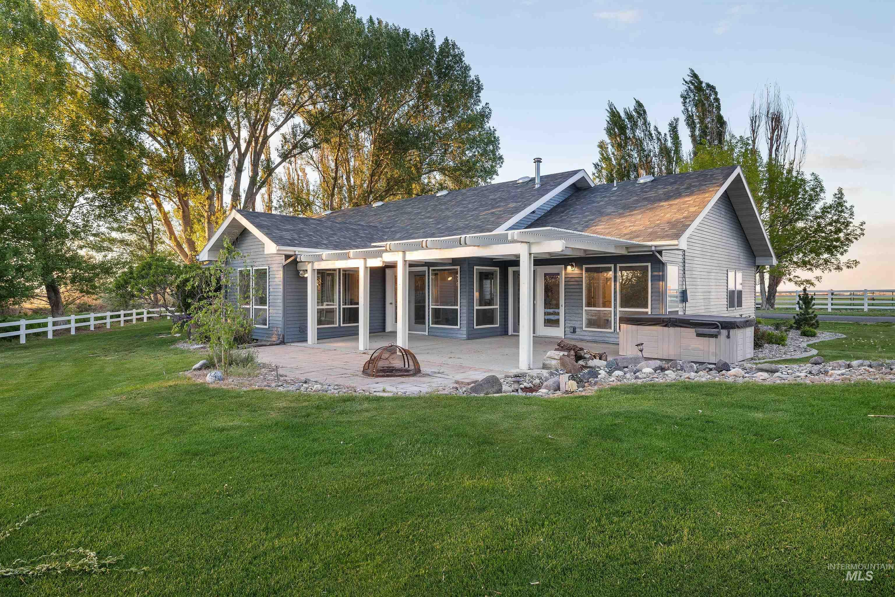 Expansive rear patio featuring a pergola, multiple large windows, and a built-in hot tub