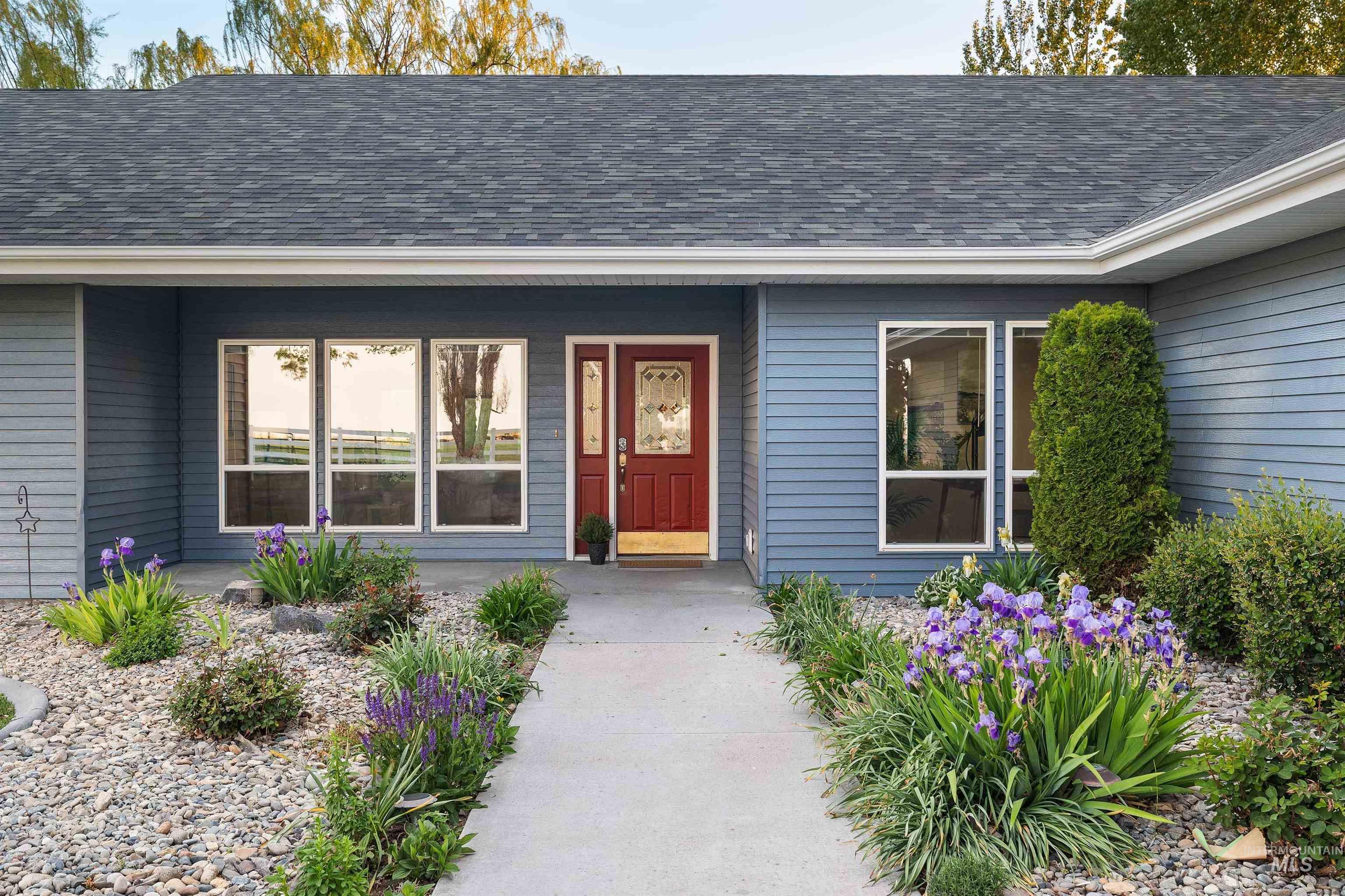 Exterior featuring blue siding, a red entry door with decorative glass, and a gray shingle roof