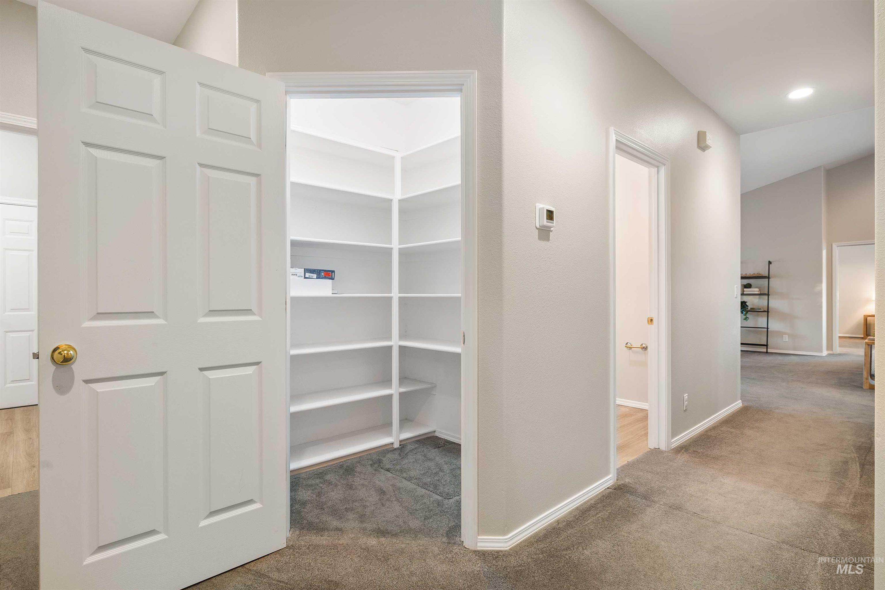 Spacious corner pantry with multiple white shelving units