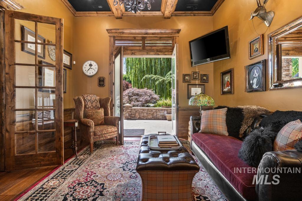 Interior room featuring a patterned area rug, wood-finish flooring, and a beamed ceiling