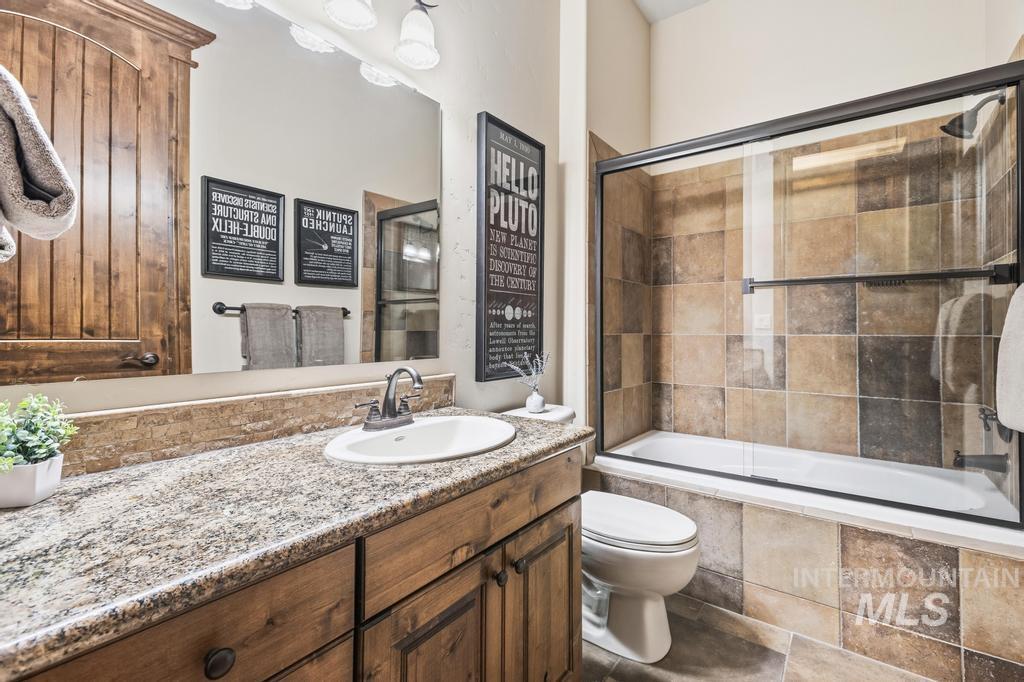 Bathroom featuring a wood-finish vanity with an undermount sink and speckled stone countertop