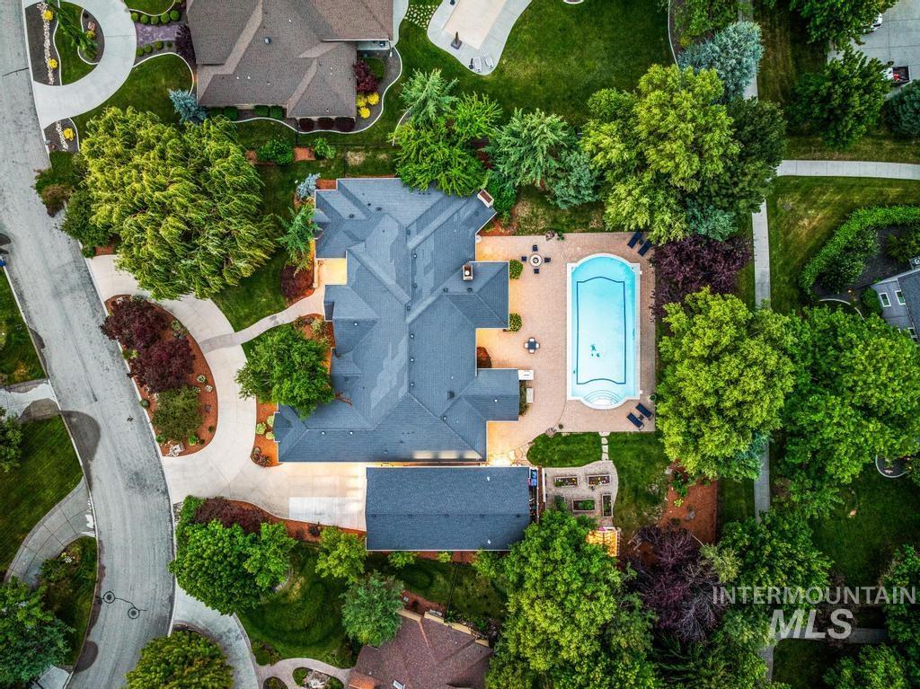 Expansive property featuring a large residence with a dark roof, a concrete pool deck, and a built-in swimming pool