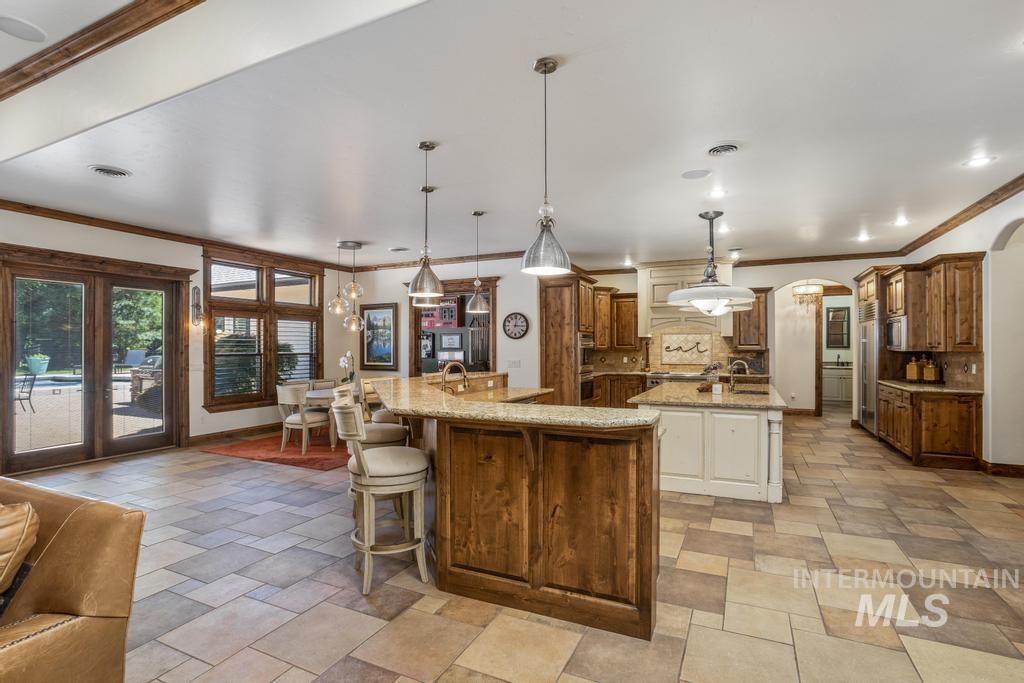 Expansive kitchen featuring dual granite-topped islands, rich wood cabinetry, and recessed lighting