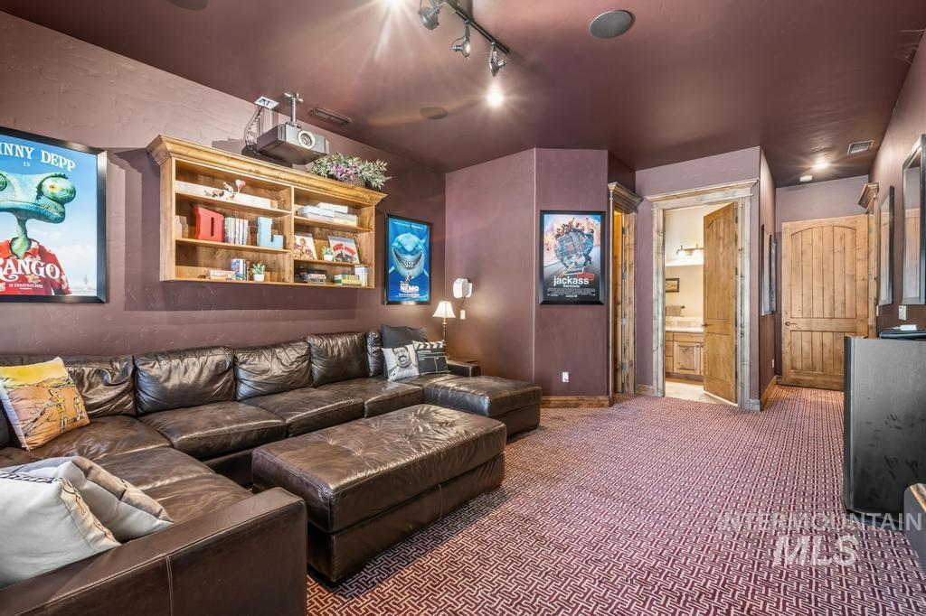 Dedicated entertainment space featuring a ceiling-mounted projector, track lighting, and a built-in wall shelf