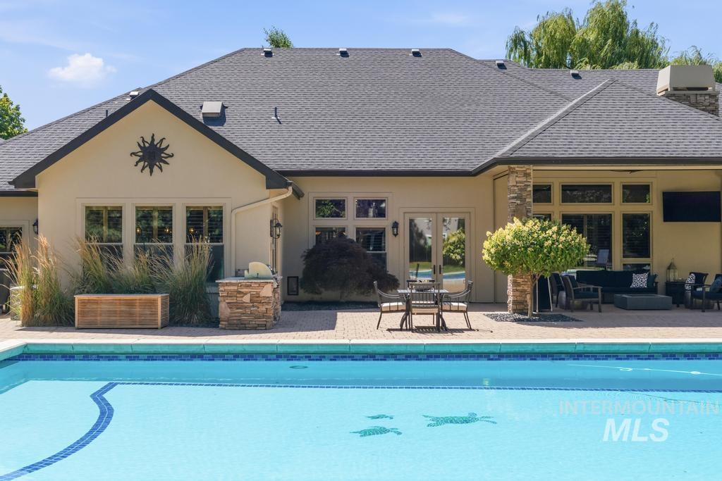 Expansive outdoor living space featuring a swimming pool with custom tile detailing, a paver patio, and a built-in outdoor grill station