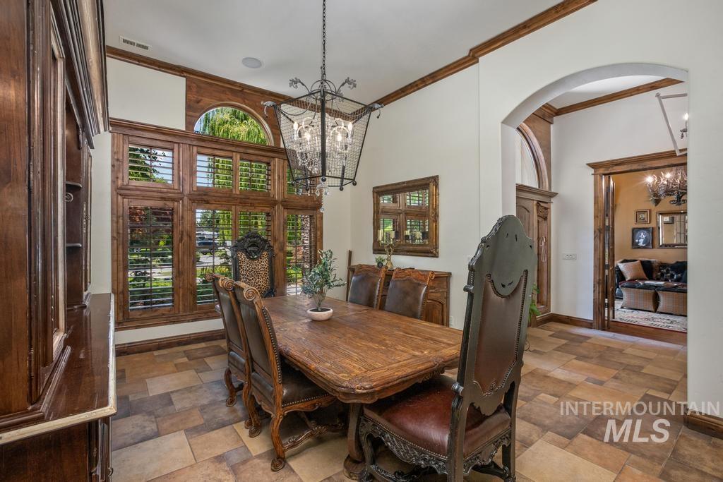 Formal dining space featuring a large window array with arched transom, wood plantation shutters, and detailed wood trim