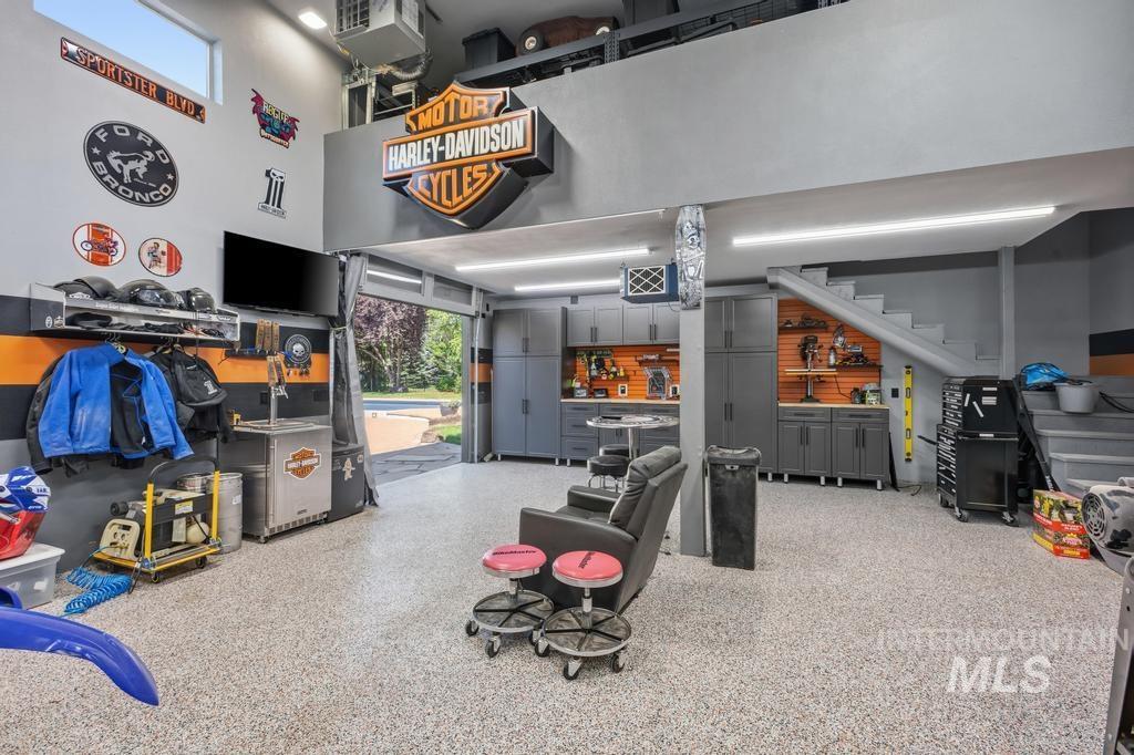 High-ceiling utility space featuring an epoxy-coated floor, integrated cabinetry, and an upper-level mezzanine