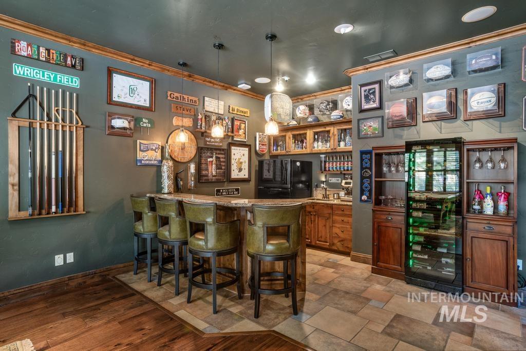 Built-in bar with wood-finish cabinetry, a stone countertop, and integrated sink