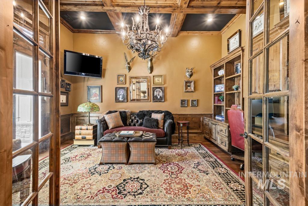 Coffered wood beam ceiling featuring recessed lighting and a central chandelier