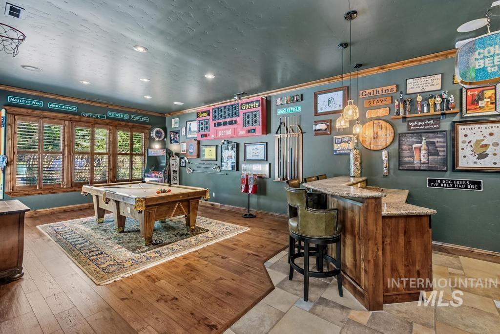 Recreation room featuring wood-finish flooring, recessed lighting, and a built-in bar with granite countertop