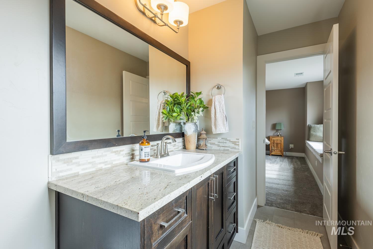 Bathroom with vanity, light colored carpet, tasteful backsplash, and light tile patterned floors