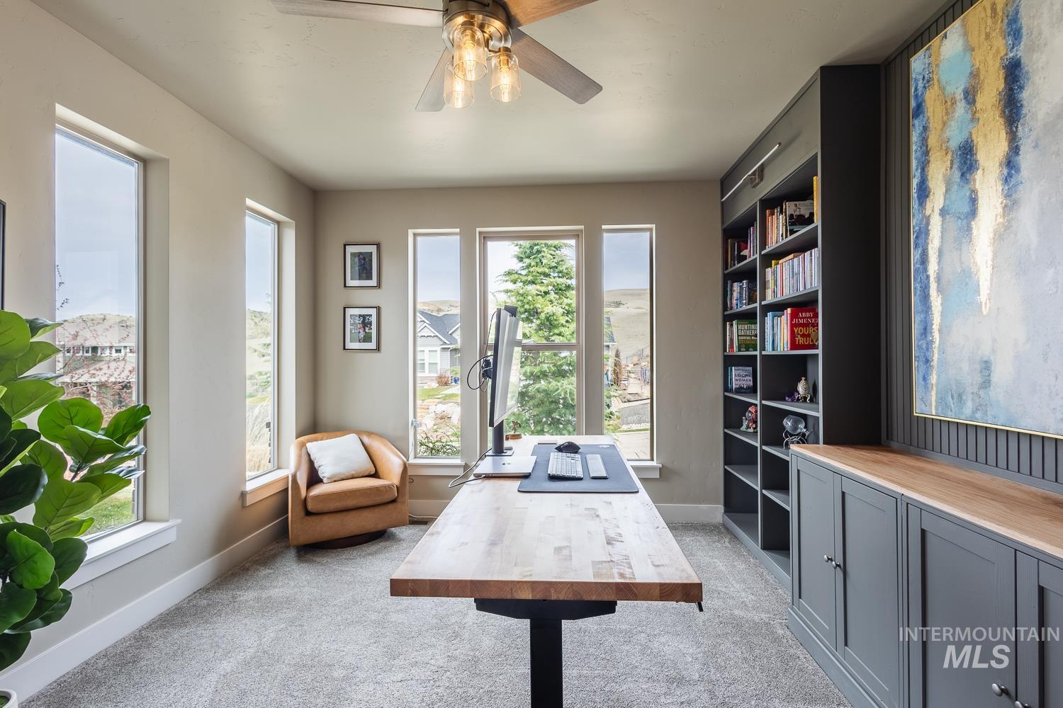 Office with light carpet and a ceiling fan