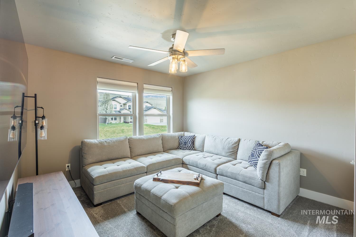 Carpeted living area with baseboards and a ceiling fan