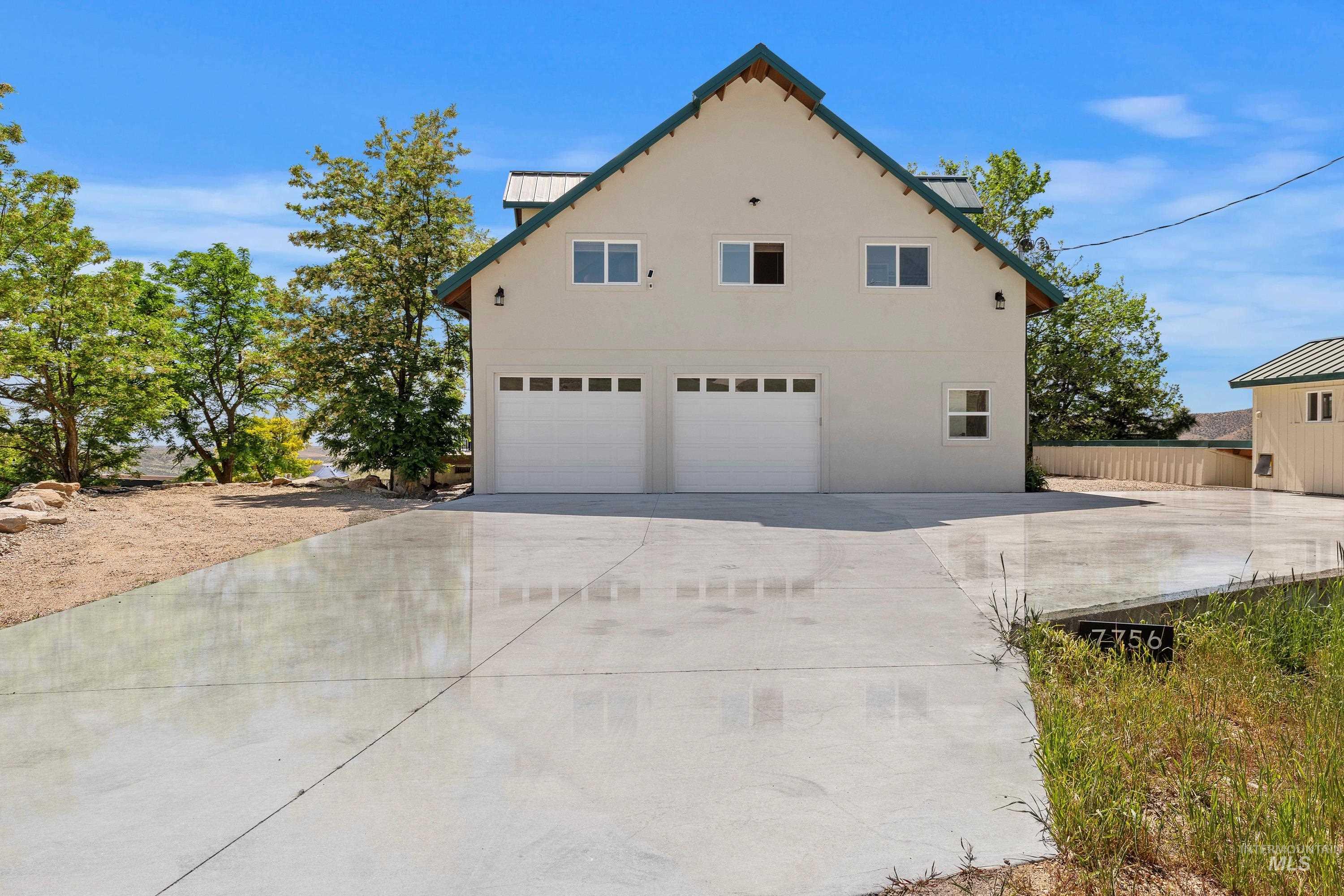View of home's exterior featuring a garage, a metal roof, a standing seam roof, driveway, and stucco siding