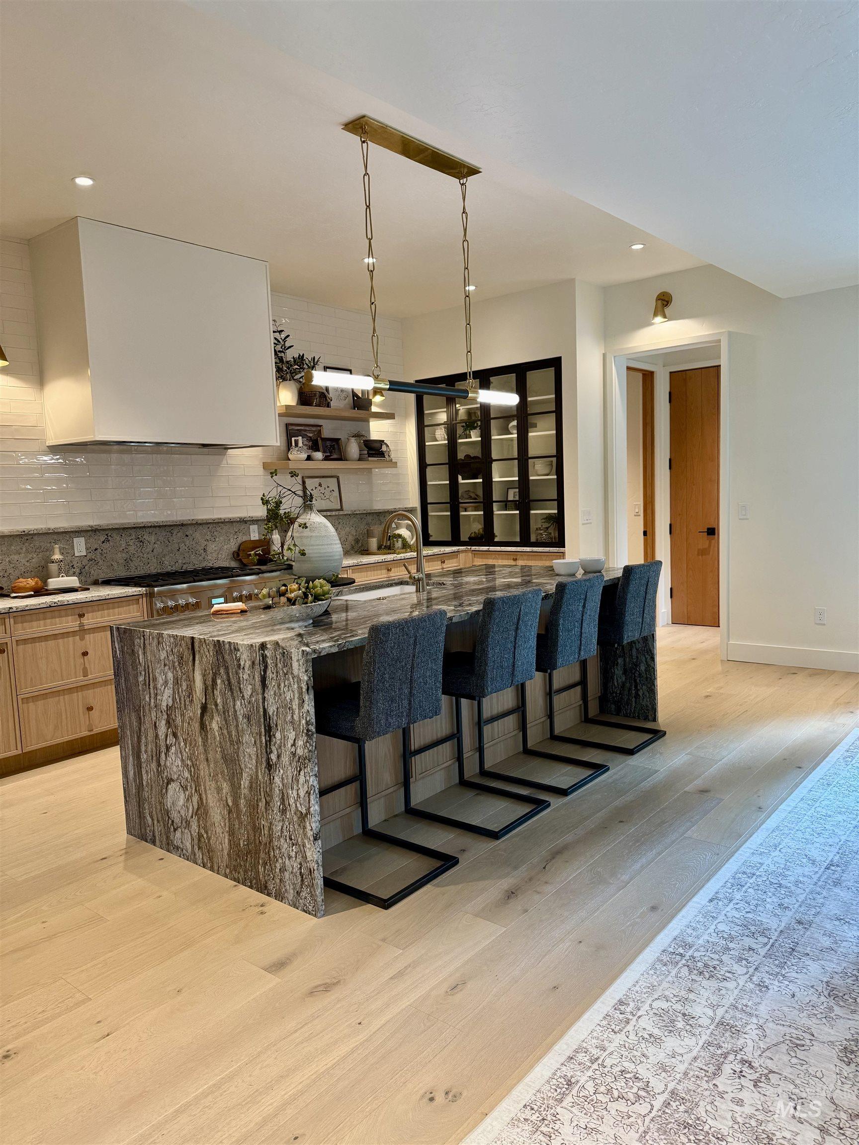 Bar featuring light wood-style flooring, dark stone counters, recessed lighting, open shelves, and decorative light fixtures