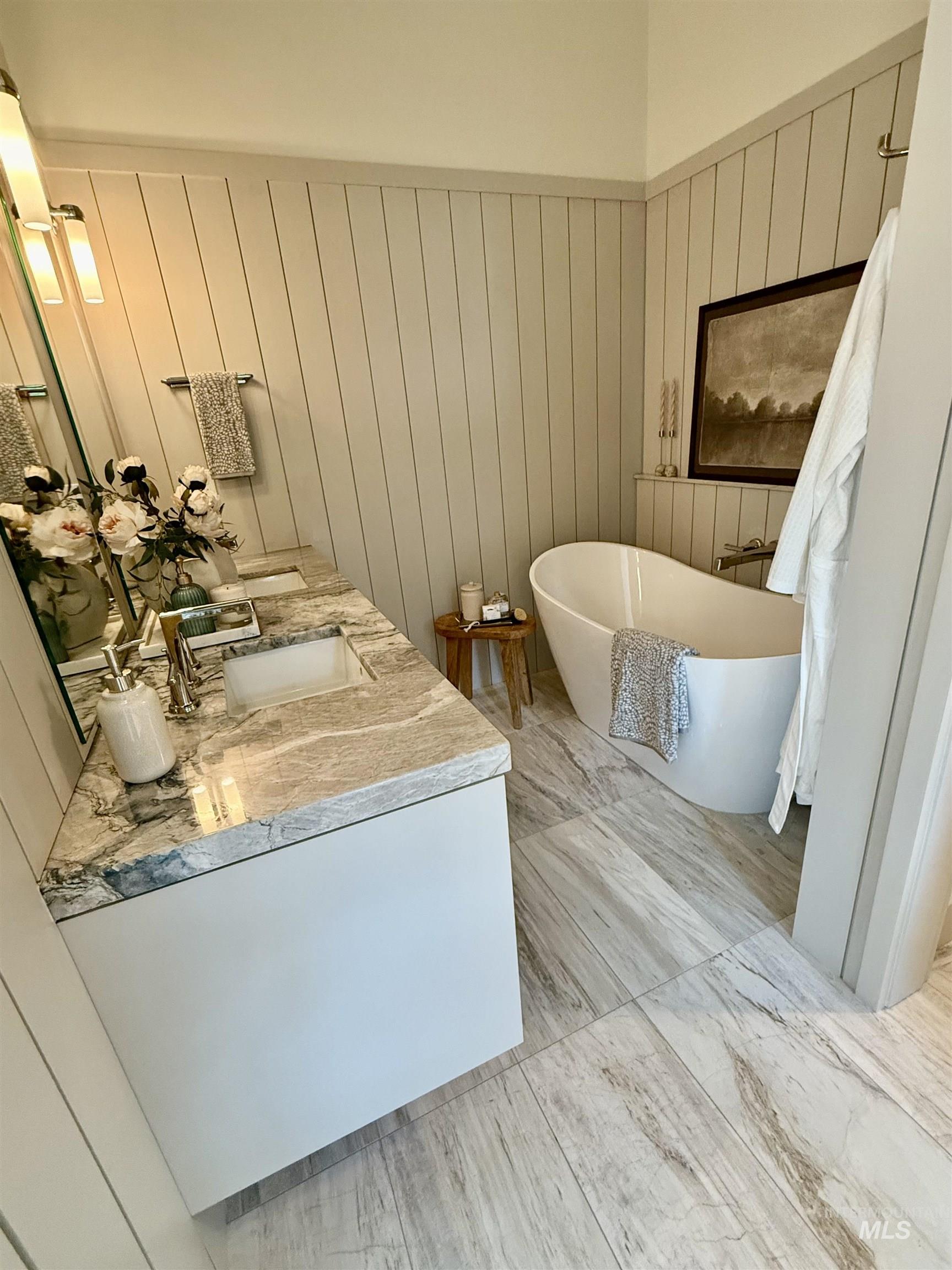 Bathroom featuring double vanity, a soaking tub, and wooden walls