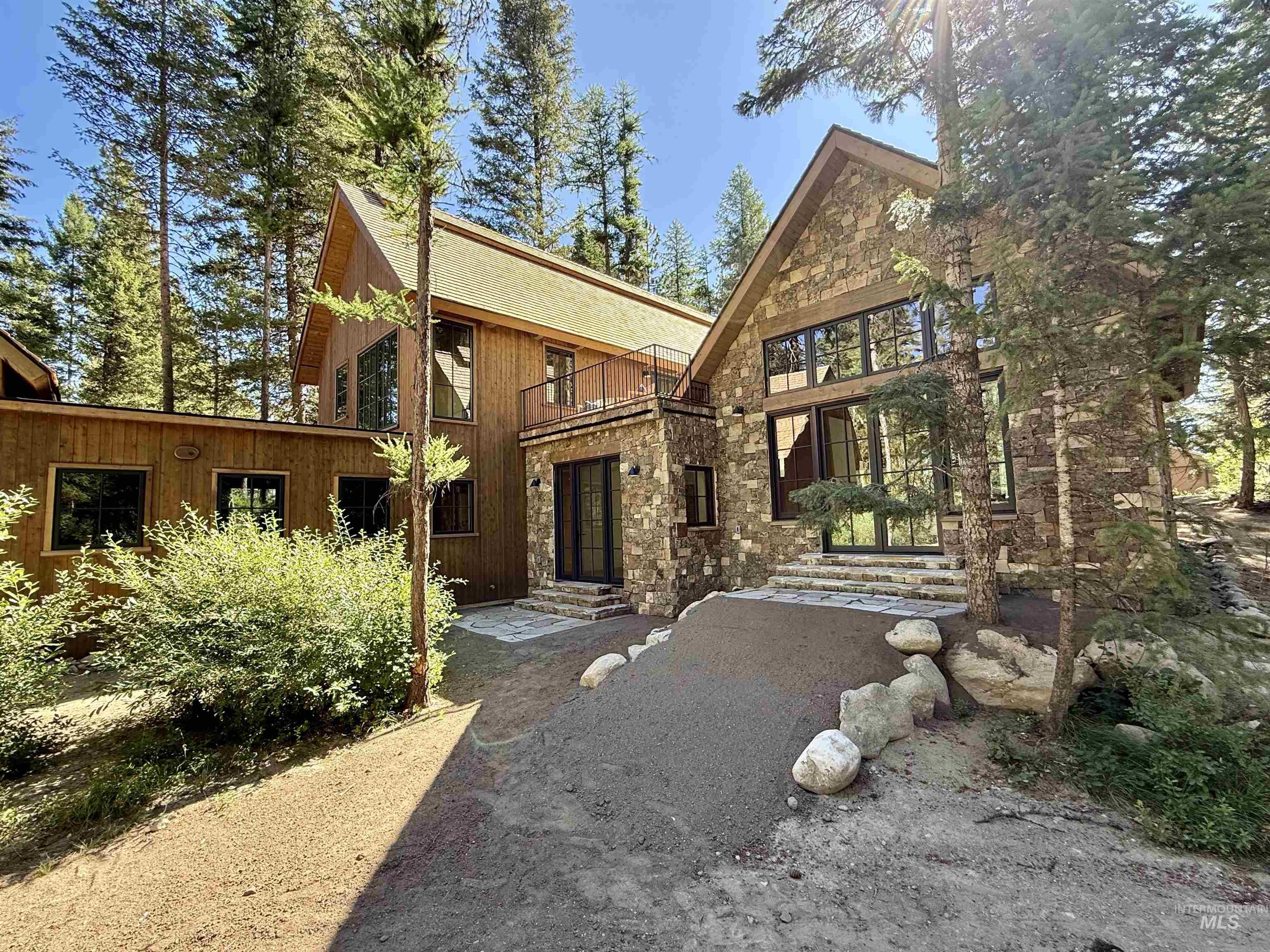 Back of house with stone siding and a balcony