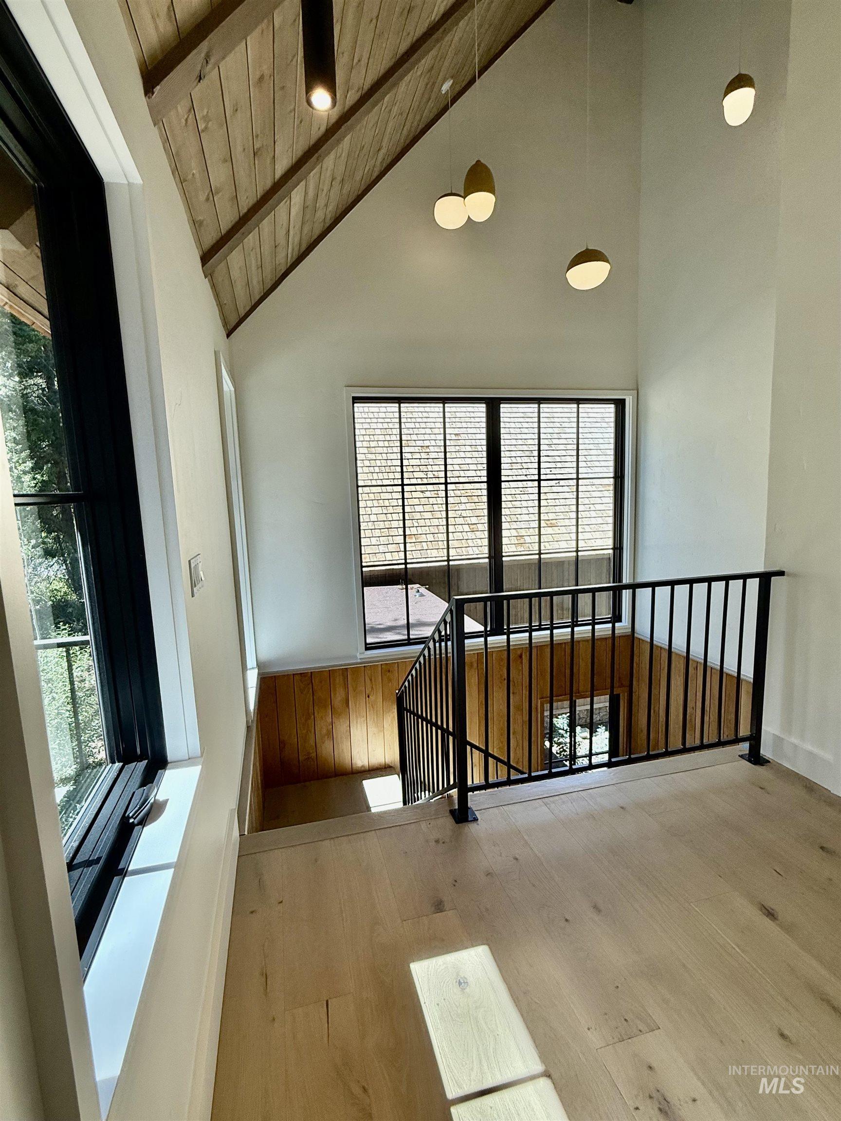 Corridor featuring hardwood / wood-style flooring, a wooden ceiling with exposed beams, high vaulted ceiling, and an upstairs landing