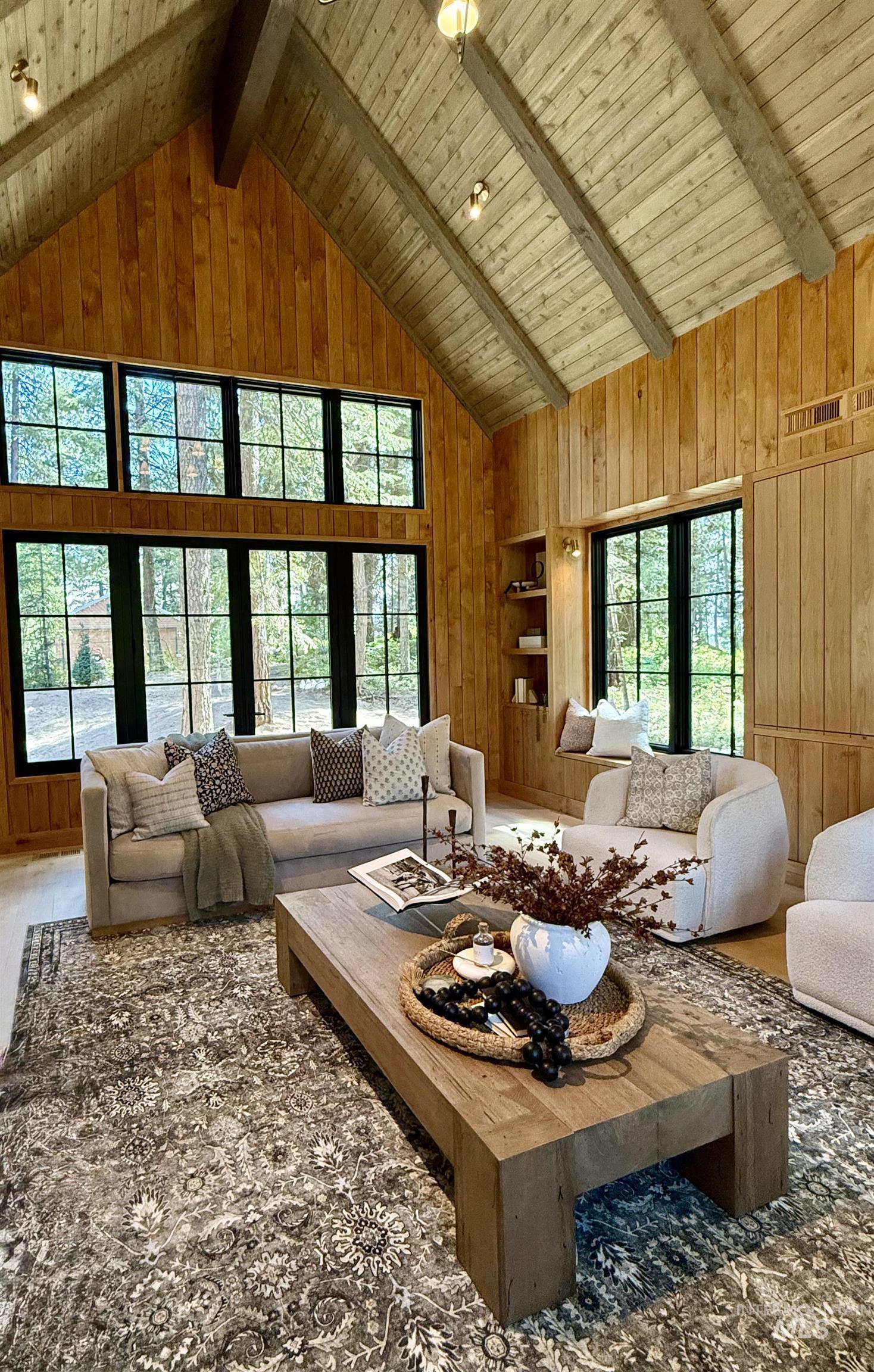 Living area featuring wooden walls, high vaulted ceiling, and a wood ceiling with exposed beams