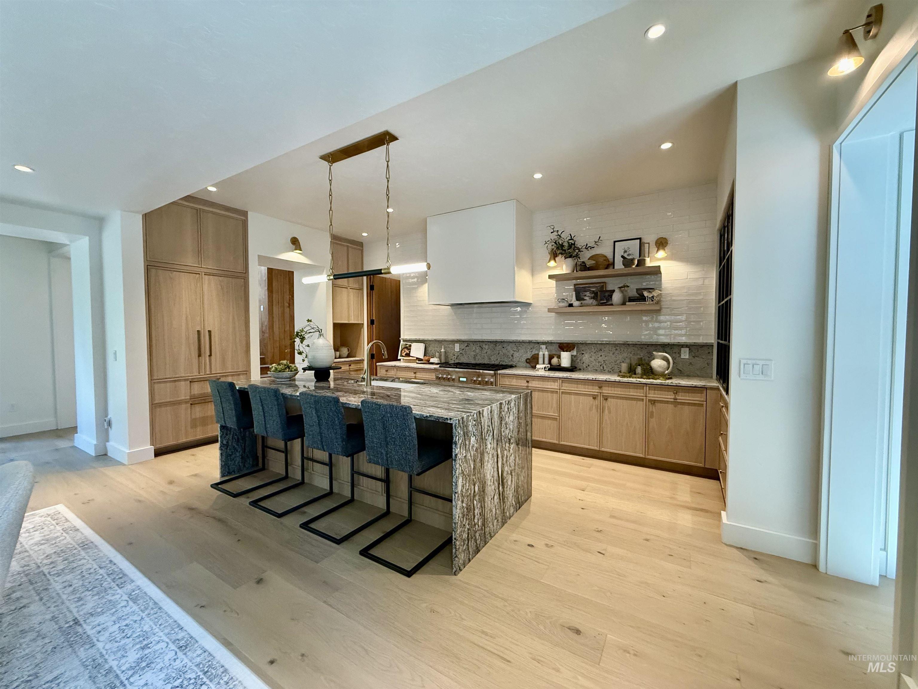 Kitchen featuring light stone counters, open shelves, a breakfast bar area, light brown cabinets, and modern cabinets