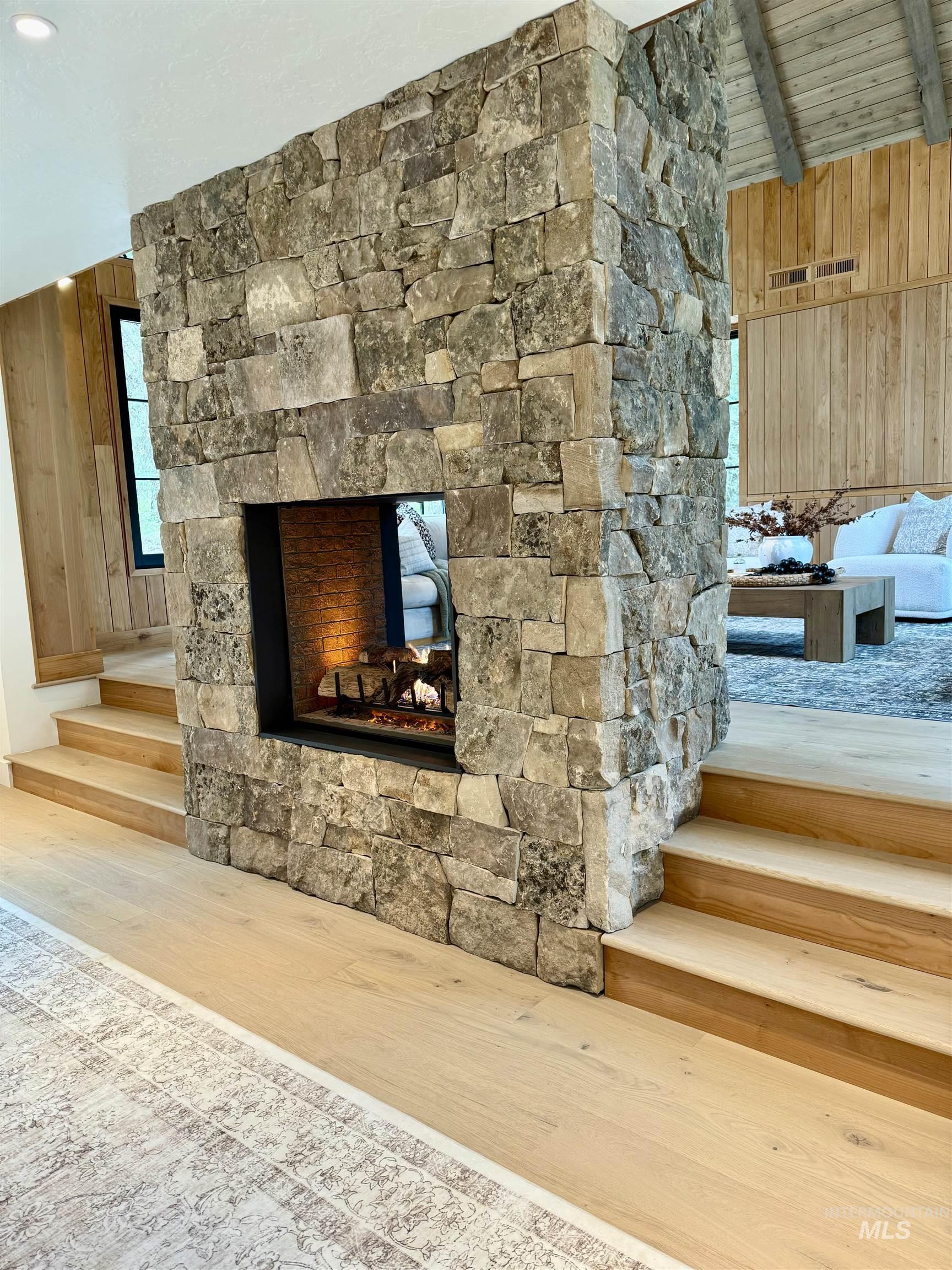 Detailed view of wooden walls, wood finished floors, a fireplace, and a wooden ceiling with exposed beams