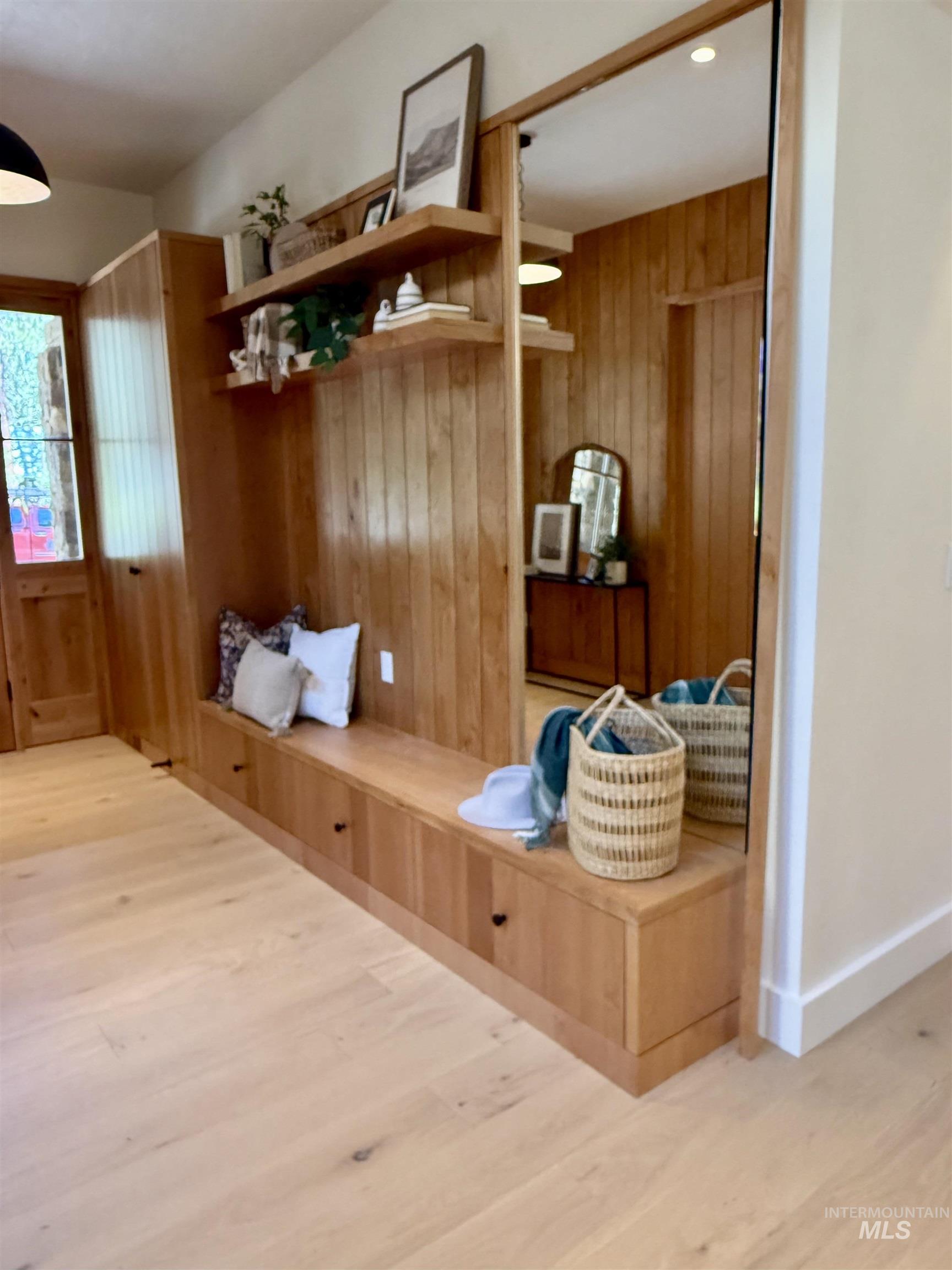 Mudroom featuring light wood finished floors and wooden walls