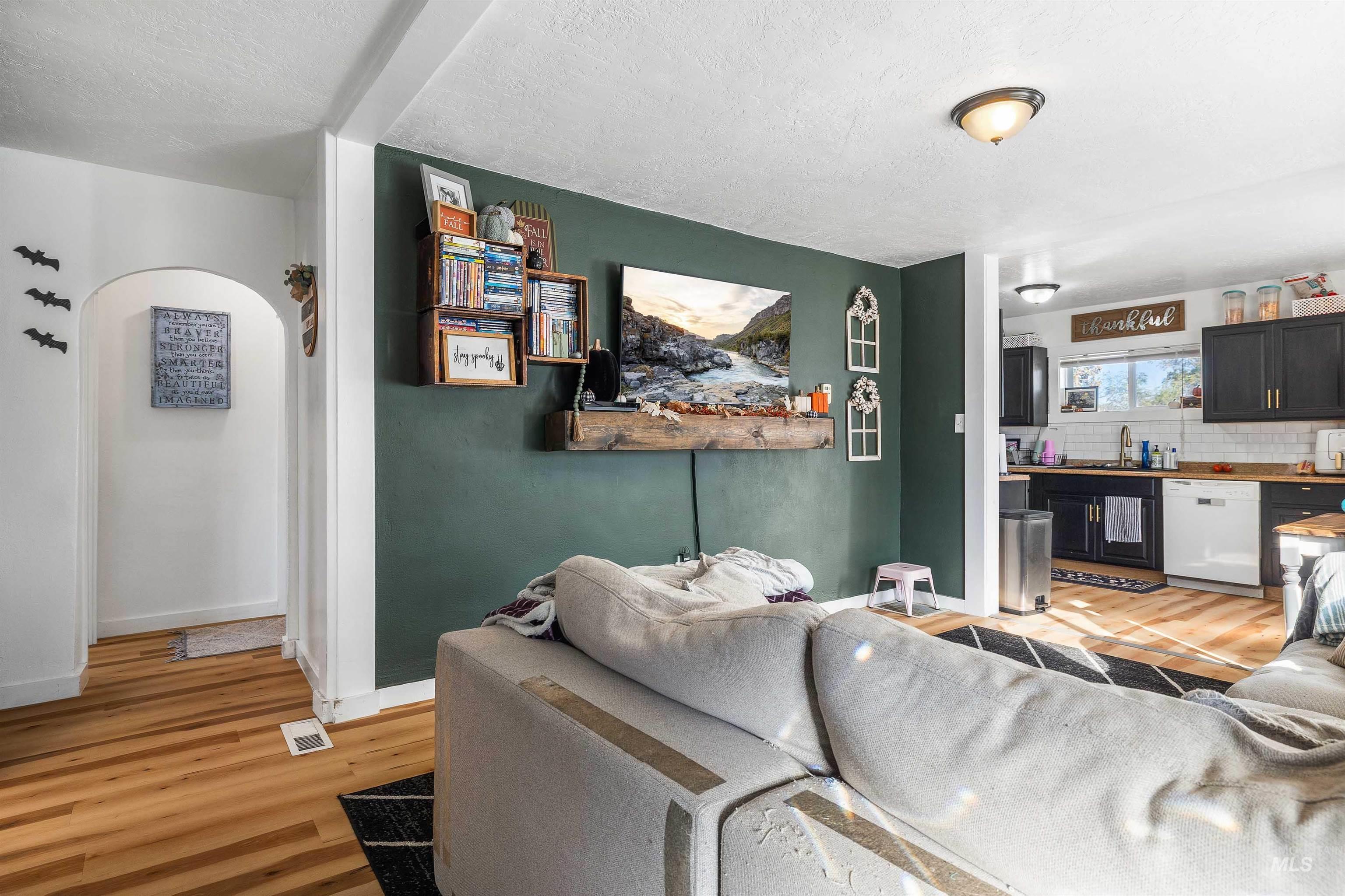 Living area with light wood-style floors, a textured ceiling, and arched walkways