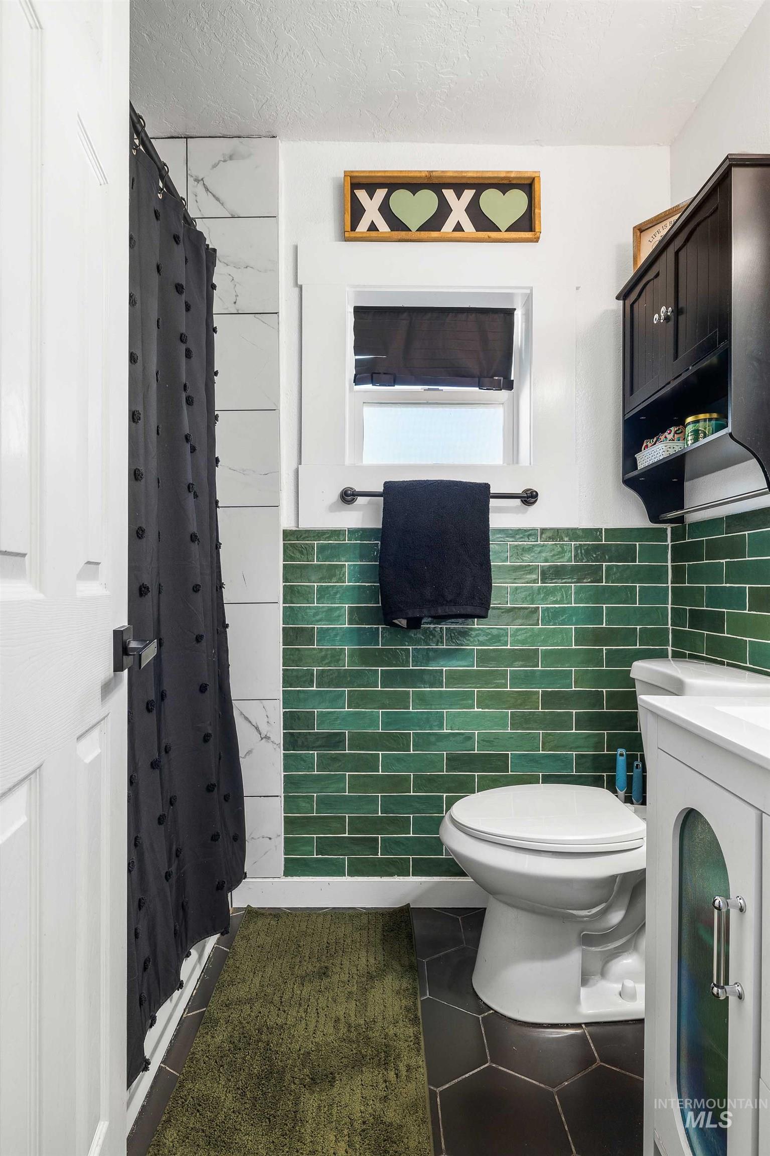 Full bath with a stall shower, a textured ceiling, vanity, tile walls, and dark tile patterned floors