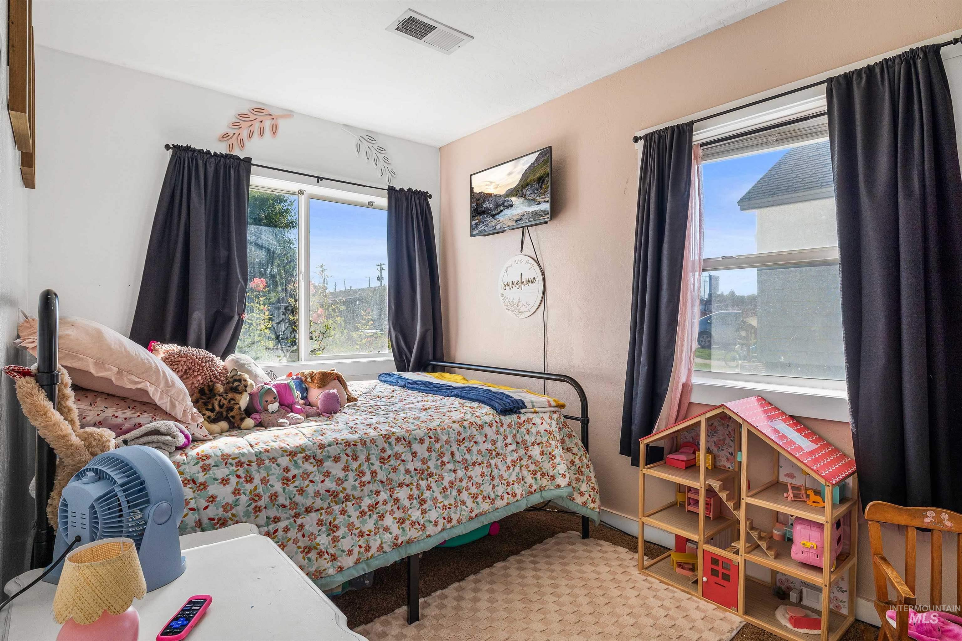 Bedroom featuring multiple windows and light colored carpet